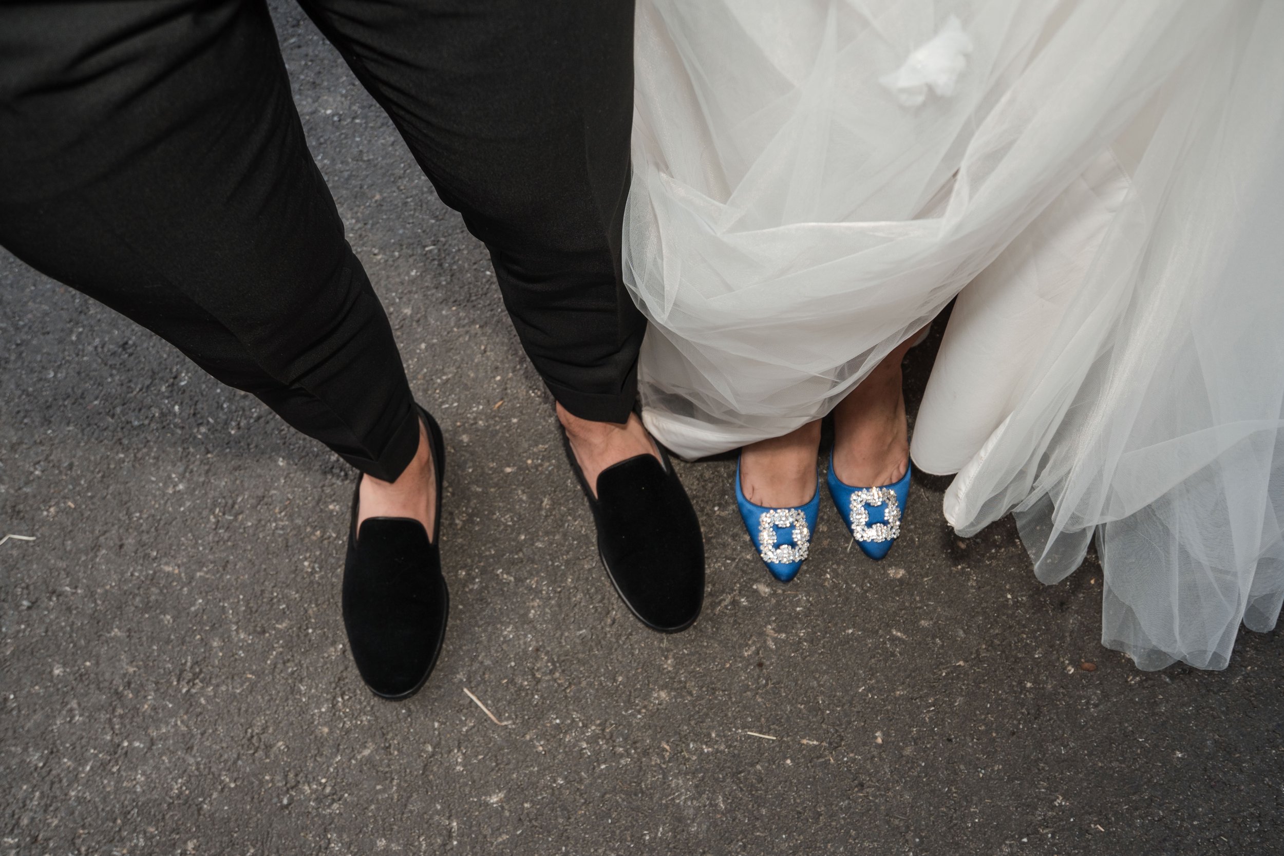 Paarfüße in formeller Kleidung und Hochzeitskleid auf einer asphaltbedeckten Oberfläche