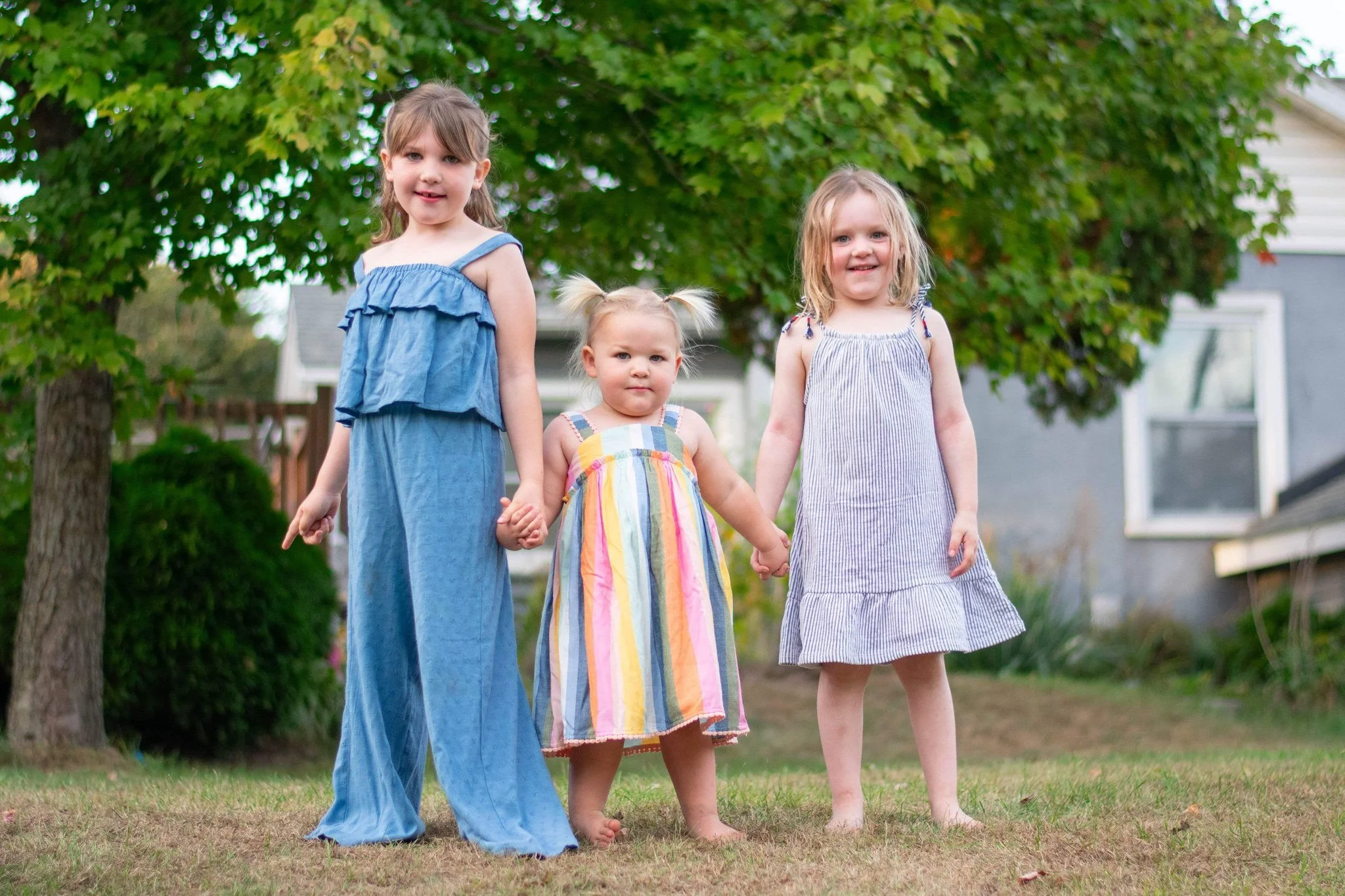 Three sisters holding hands in a backyard, family photography session in Manchester, MI
