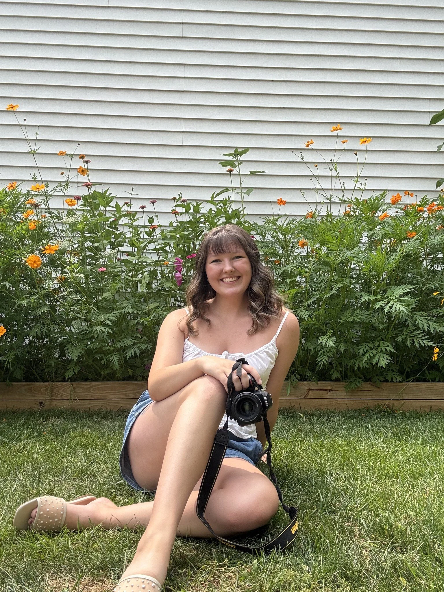 Taylor, family photographer in Manchester, MI, in her flower garden with her camera.