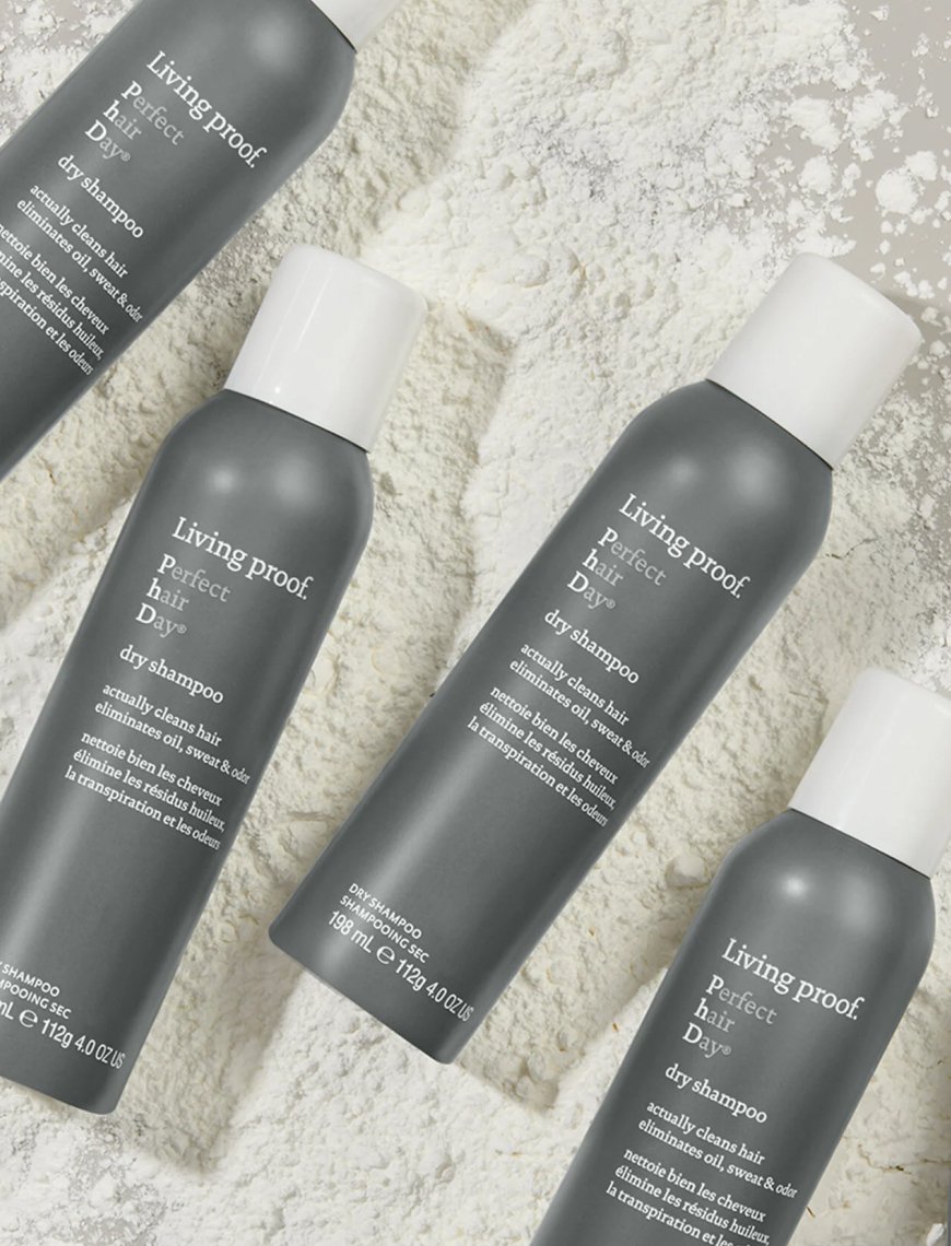 Multiple bottles of Living proof Perfect Hair Day dry shampoo on a white textured surface.