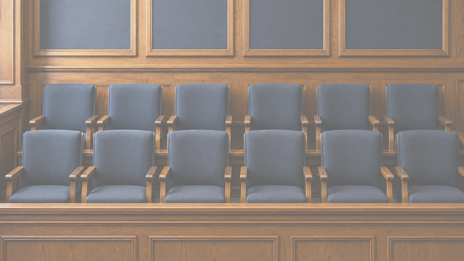 Empty courtroom with wooden paneling and blue upholstered seats.