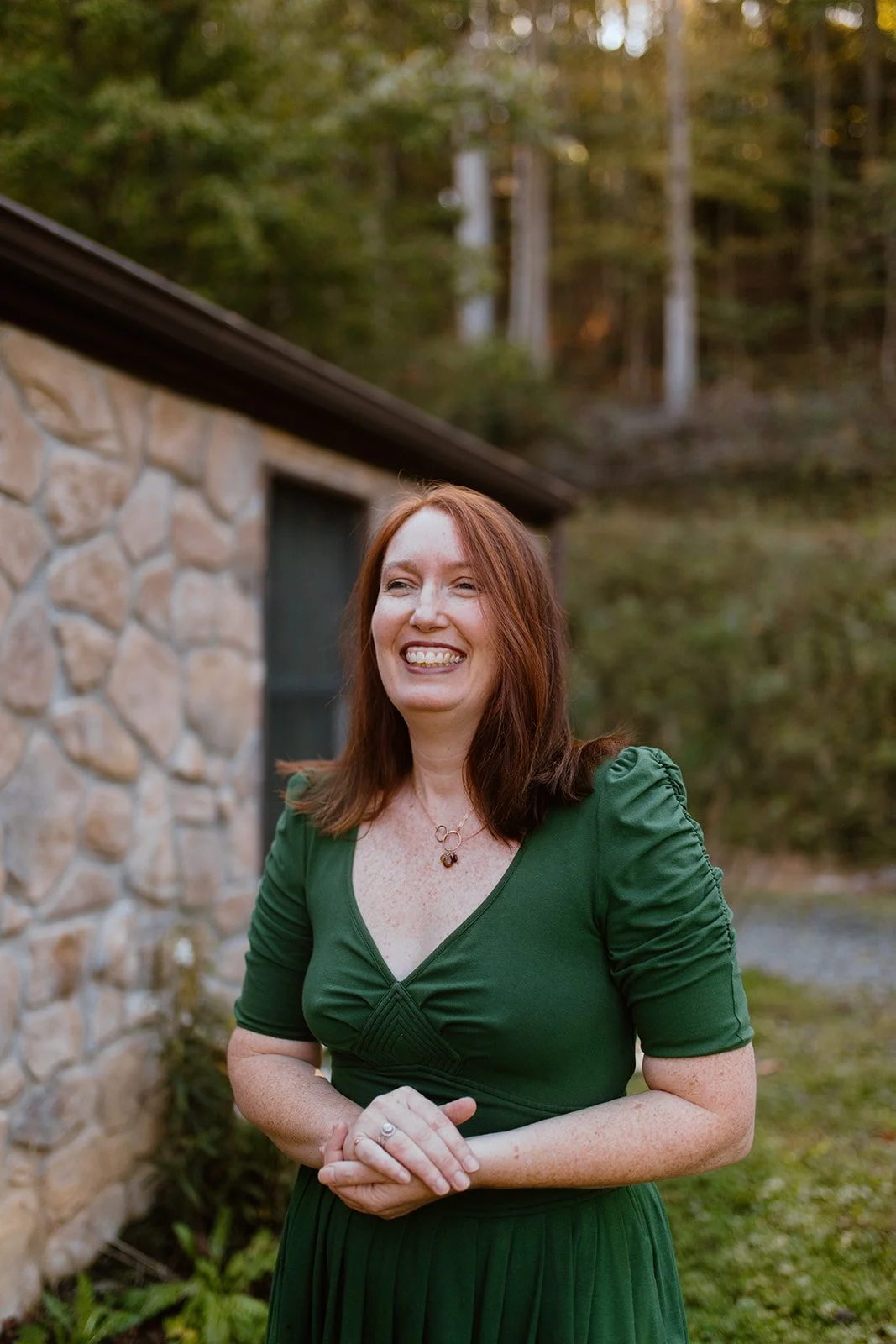 Catherine Venable Moore wearing a green dress outdoors near a stone building with trees in the background.