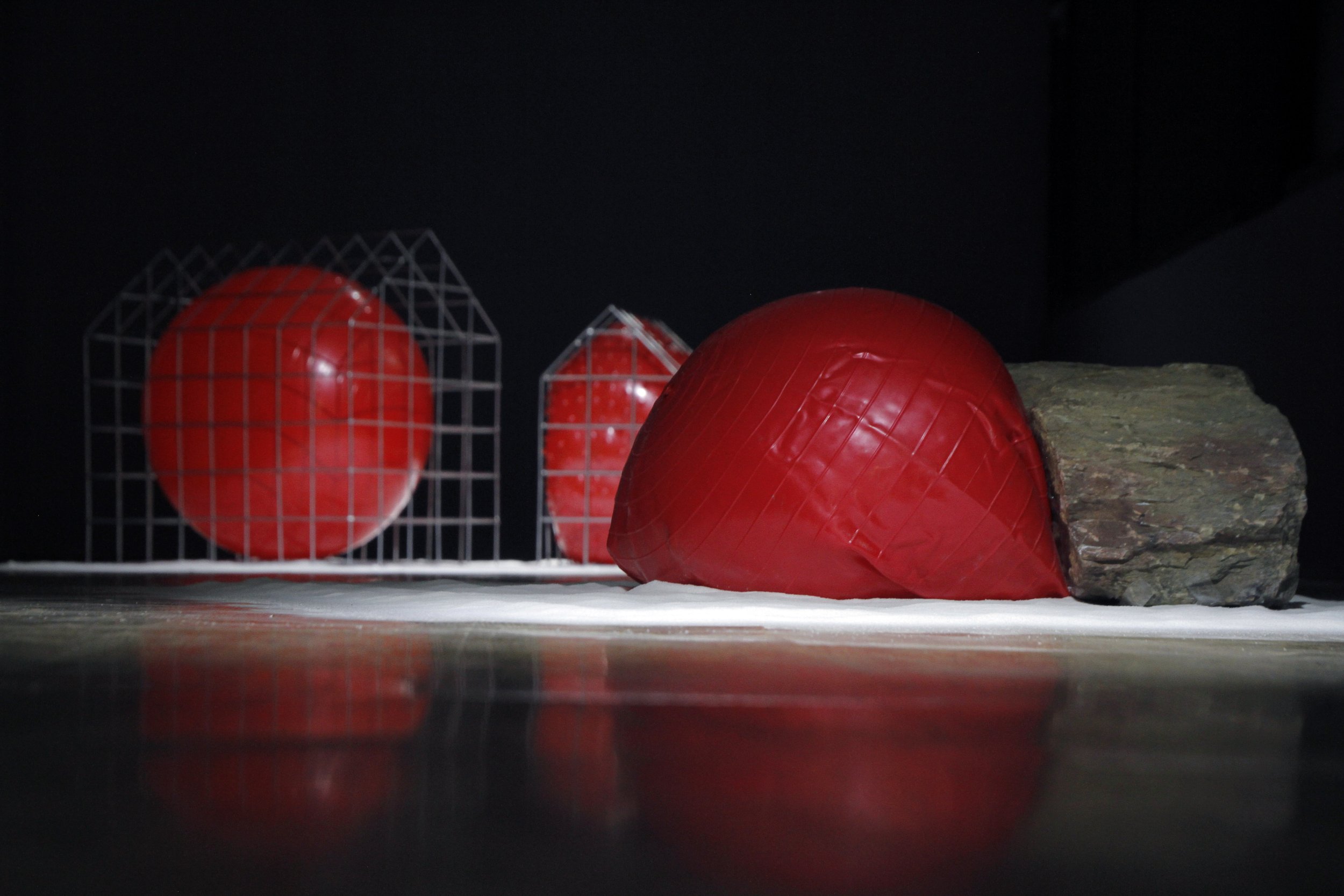 Red plastic air mattresses or flotation devices and a large rock on a snowy surface at night.