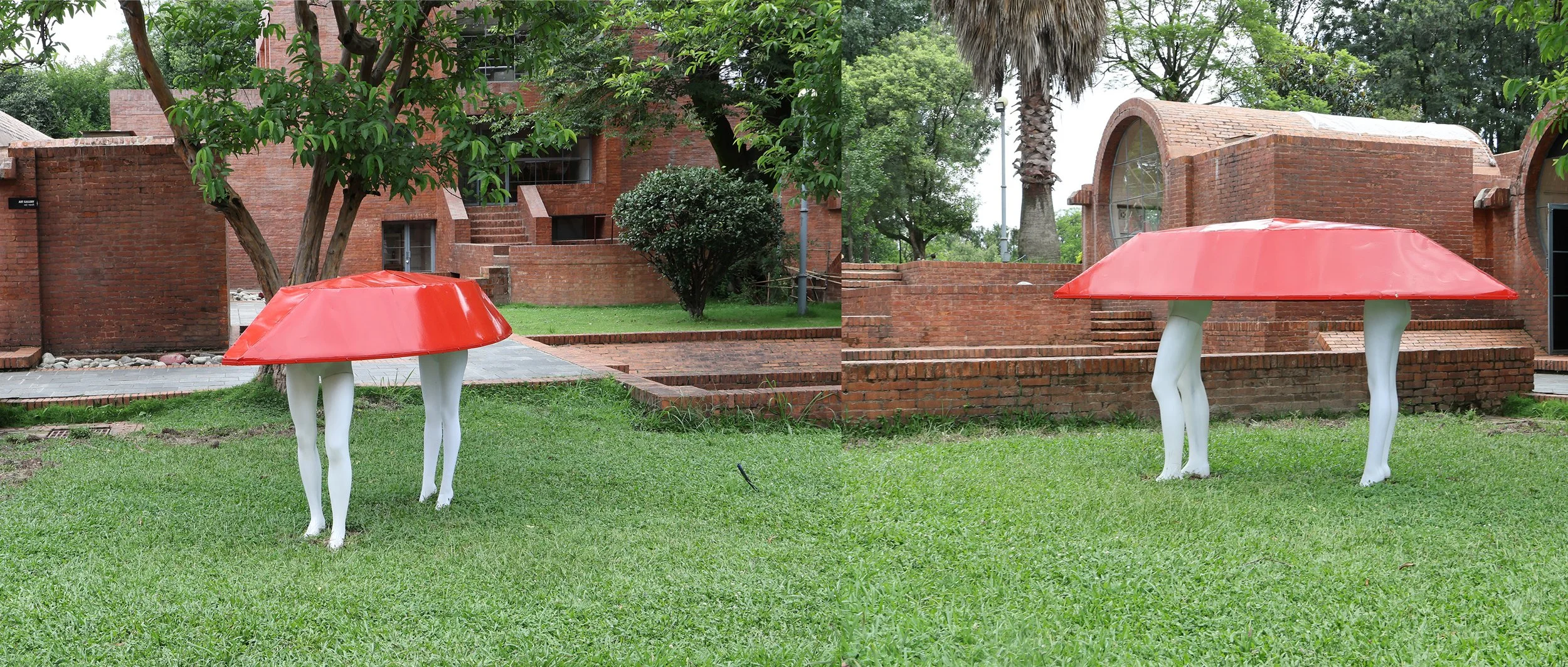 Two art sculptures of table with legs resembling horse legs with white painted limbs and red tabletops, placed on grassy area with trees and brick building in the background.