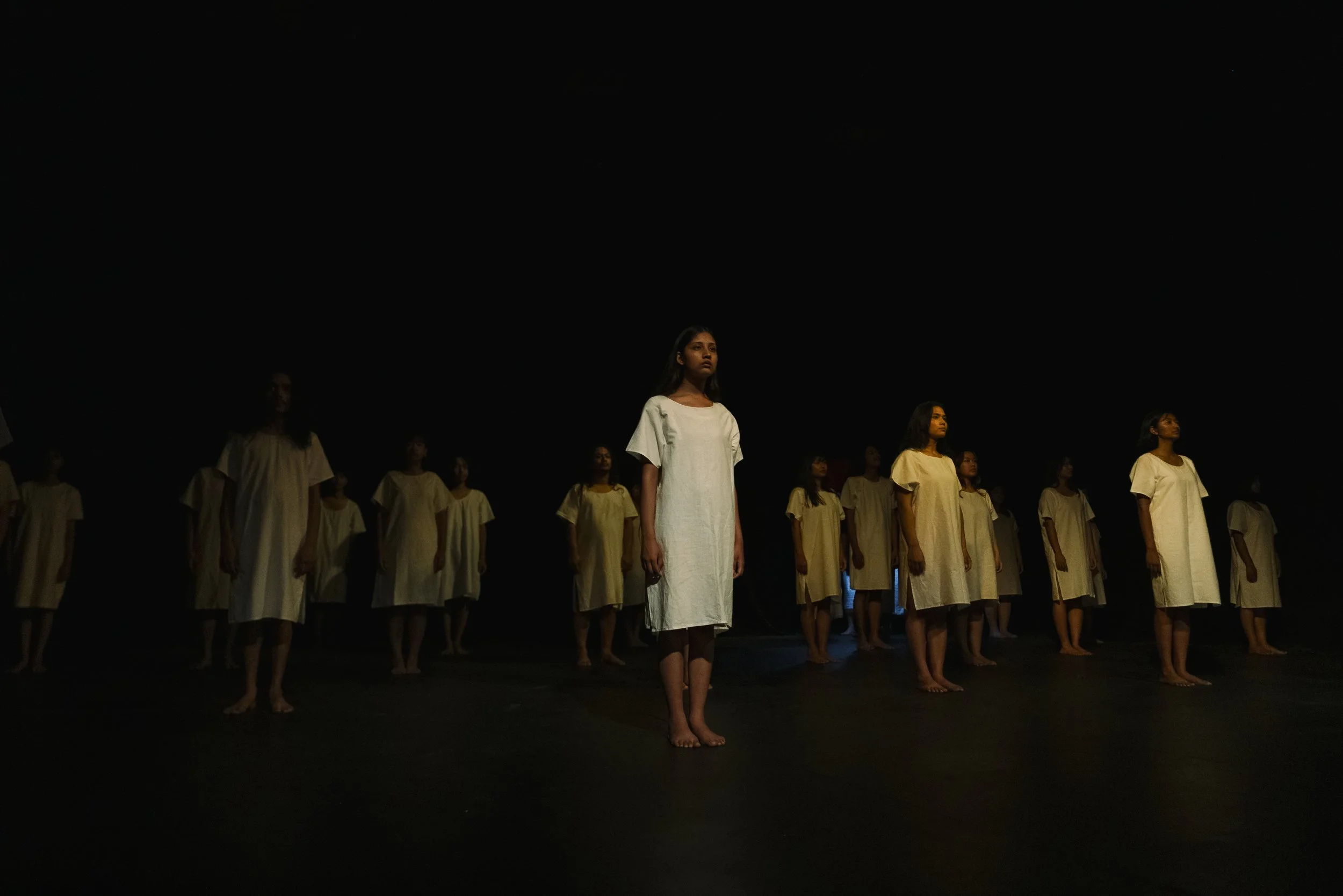 Performers standing on stage with a dark background.