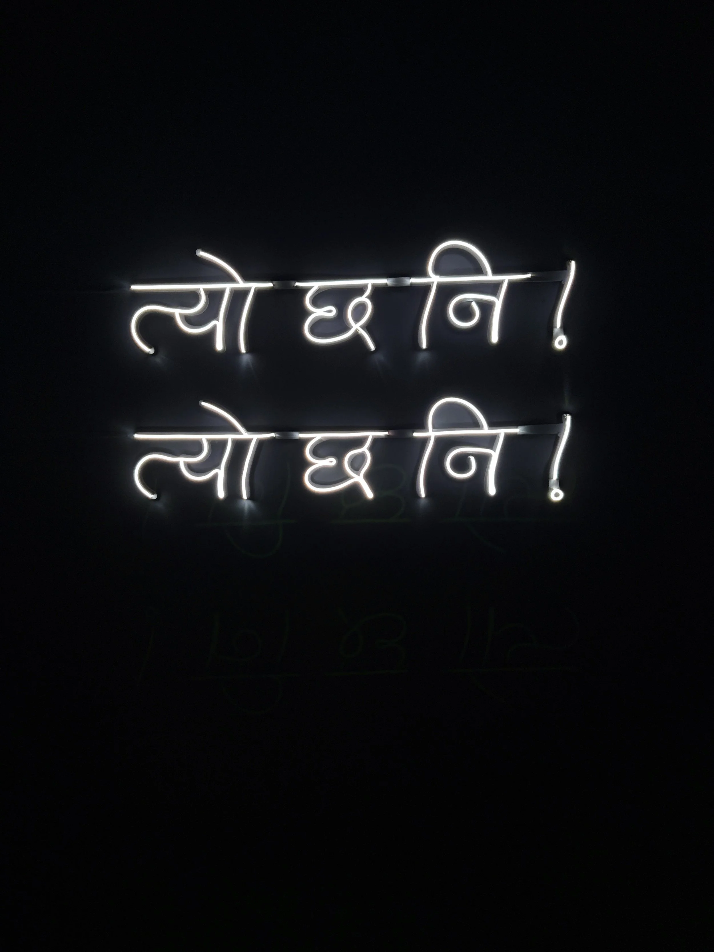 Neon sign displaying the word 'Sorry' written in Hindi script, illuminated against a dark background.