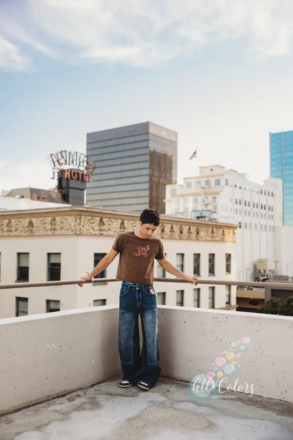 Teenage boy on a roof top with downtown buildings behind him.