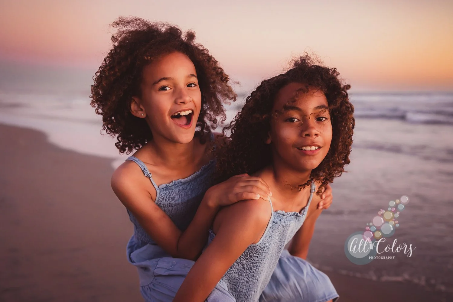 two sisters of mixed race playing piggy back on the beach