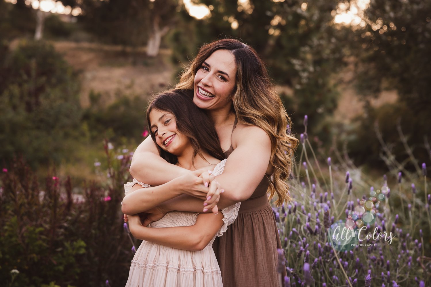 mom holding her daughter from behind on a lavender garden