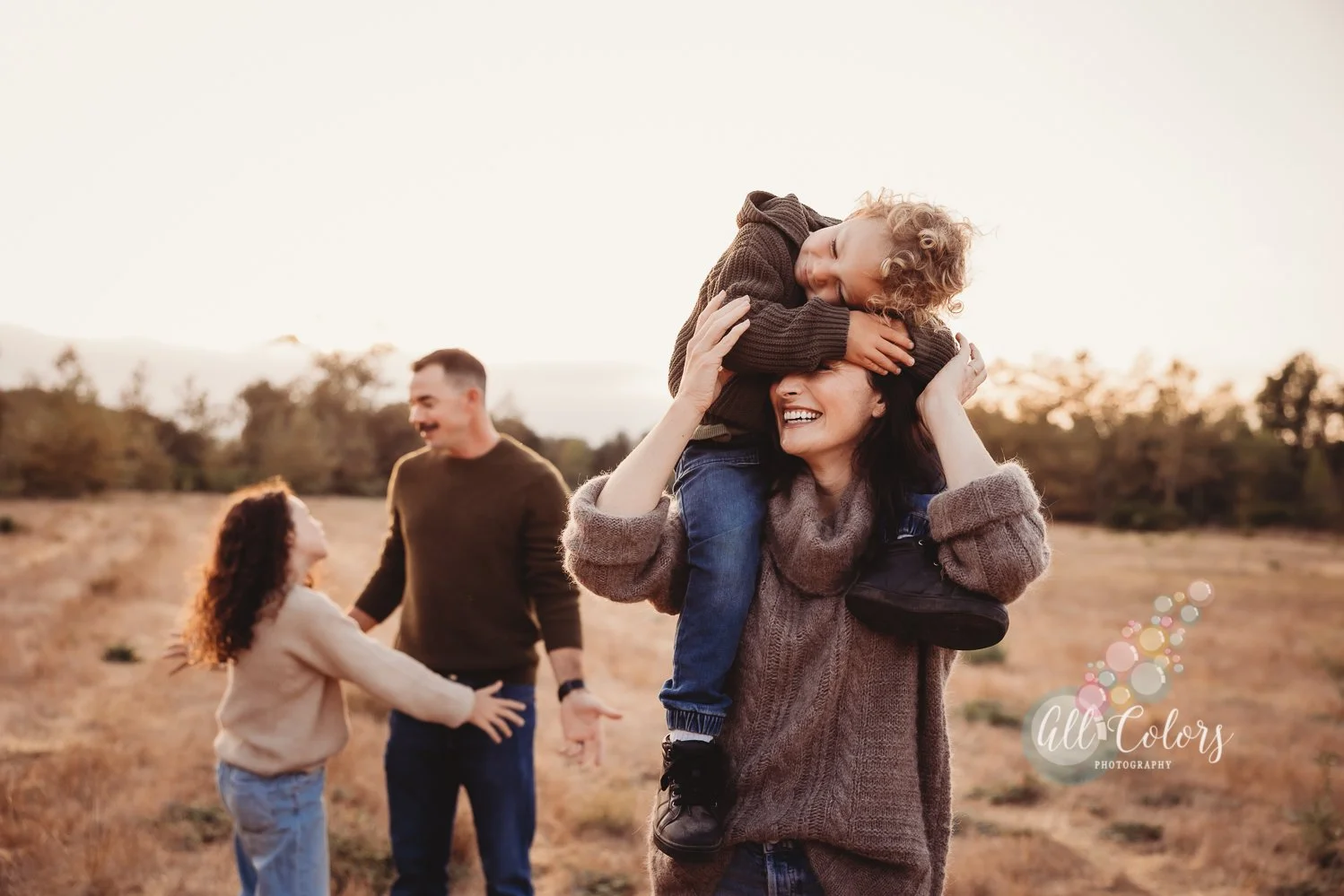 Mom, dad and two kids walking on a field in the Fall