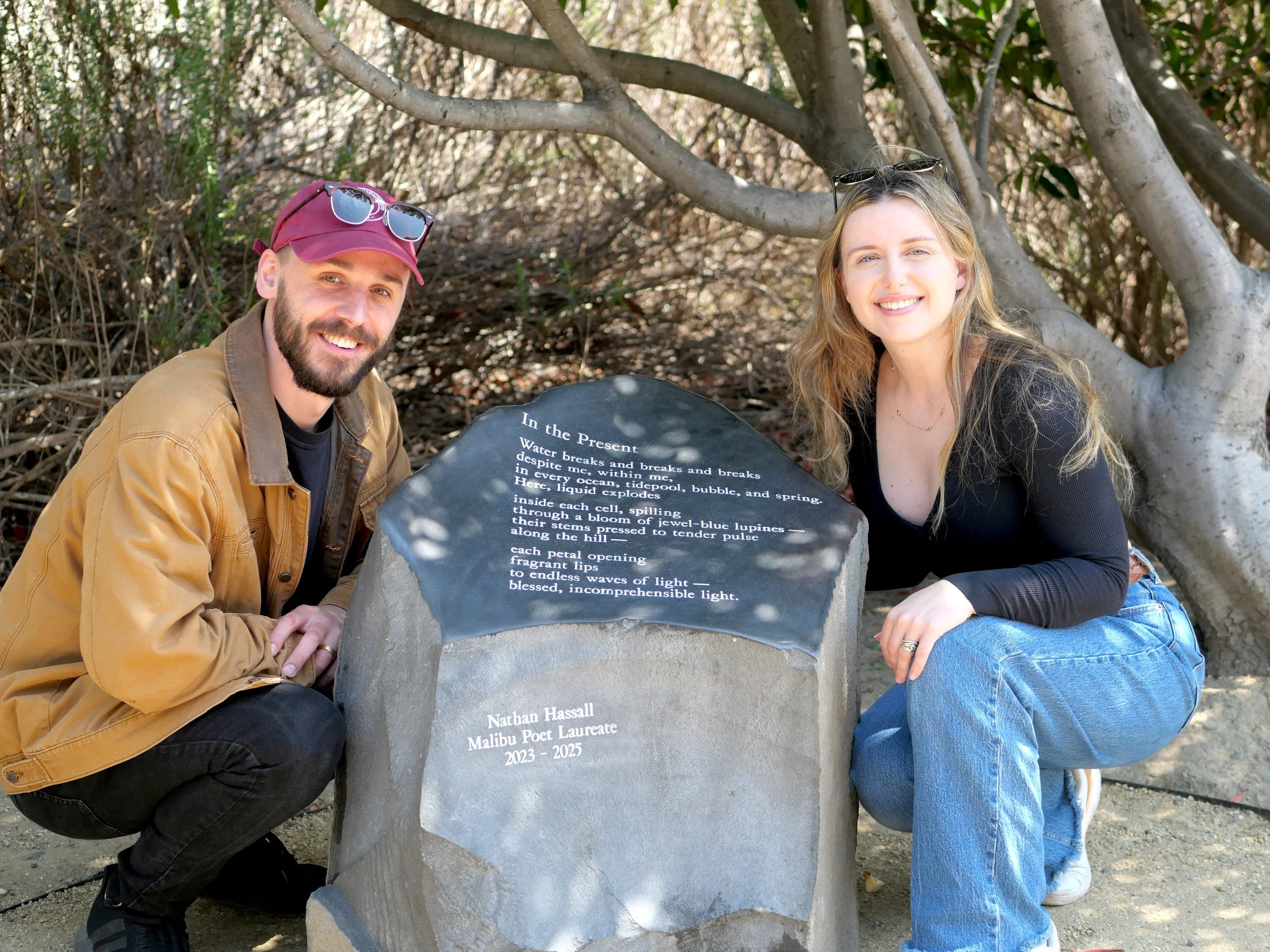 Husband and wife team, Rachael and Nathan Hassall pictured in front of Nathan Hassall's poetry stone with his original poem "In the Present," inscribed on its surface to honor Nathan's Malibu Poet Laureateship.