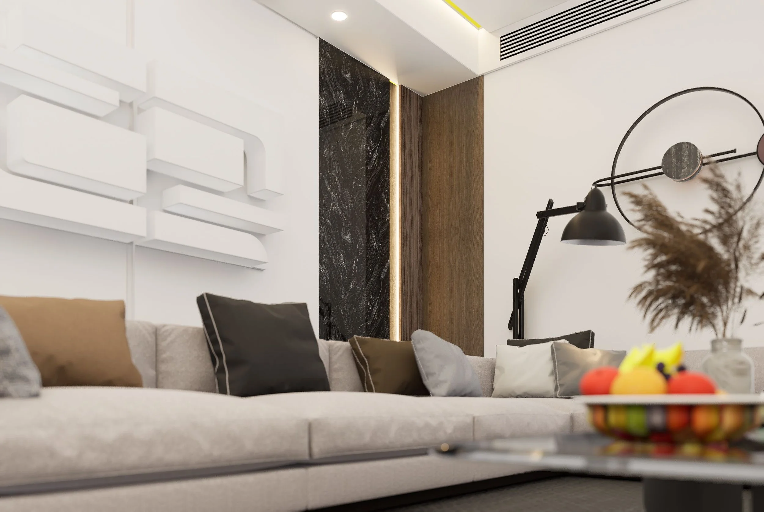 Modern living room with a white sofa, black and beige pillows, a wall with black marble and wood panels, a black wall clock, a black desk lamp, and a decorative flower arrangement.
