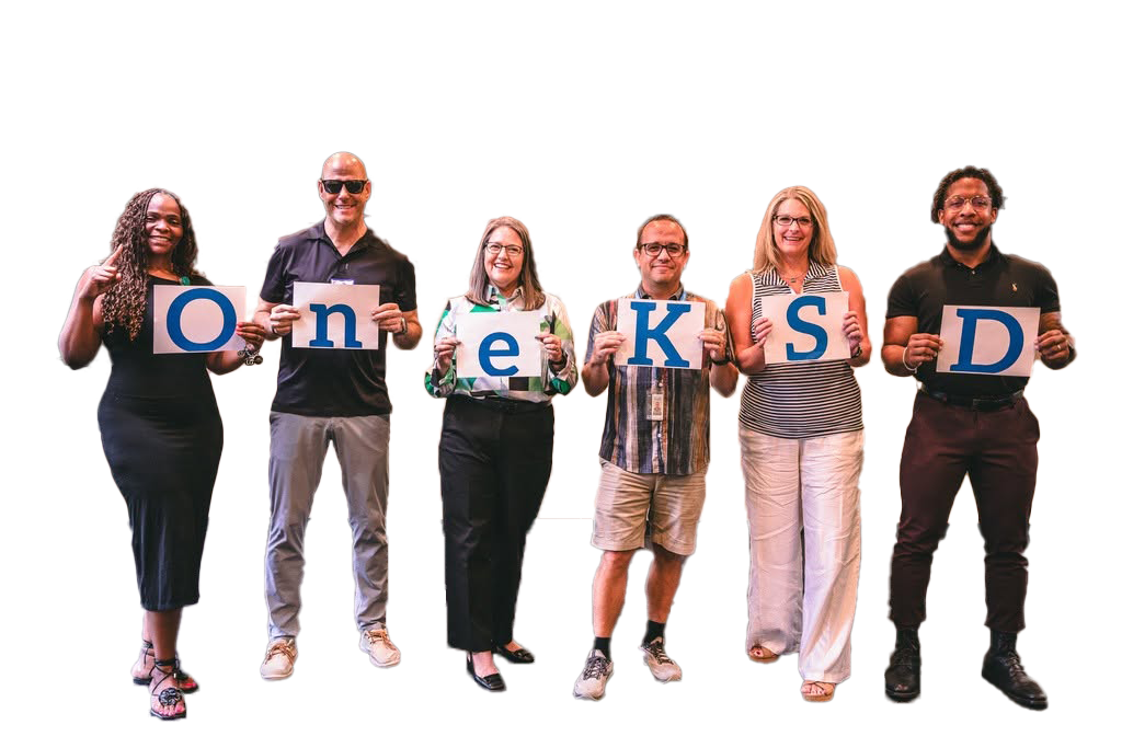 Six people standing in a row holding signs that spell out "One KSD."