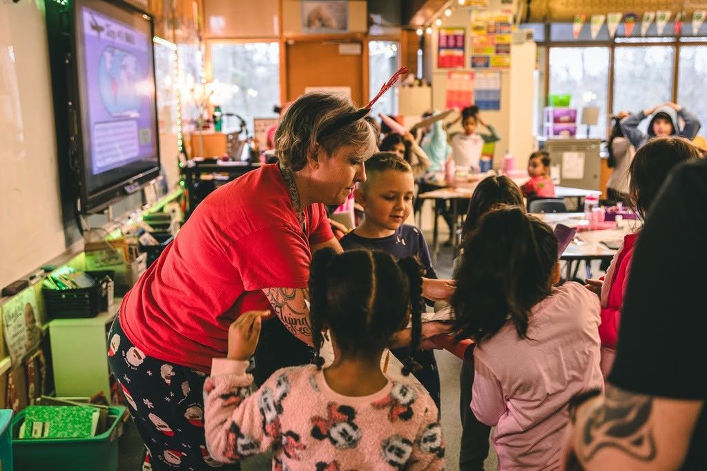 A teacher interacting with young students in a colorful classroom.