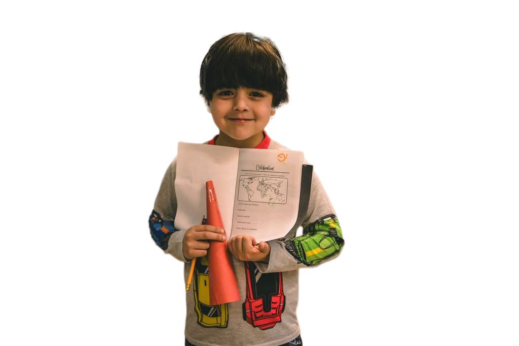 Young boy holding a workbook and a rolled-up poster, smiling at the camera.