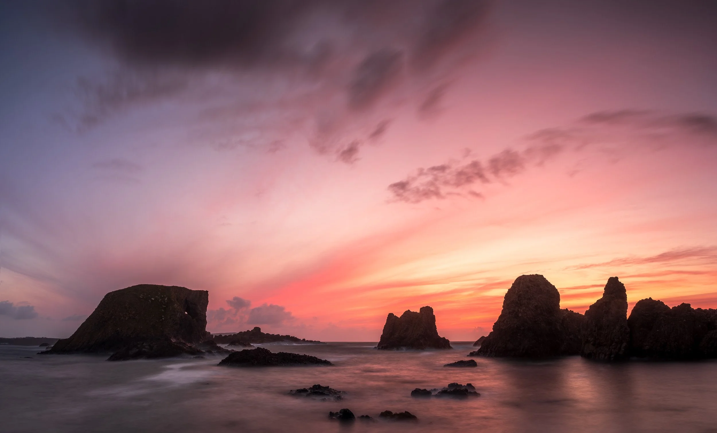 Ballintoy Elephant rock formations silhouetted beneath a pale pink sunset on the Causeway Coast, Northern Ireland.