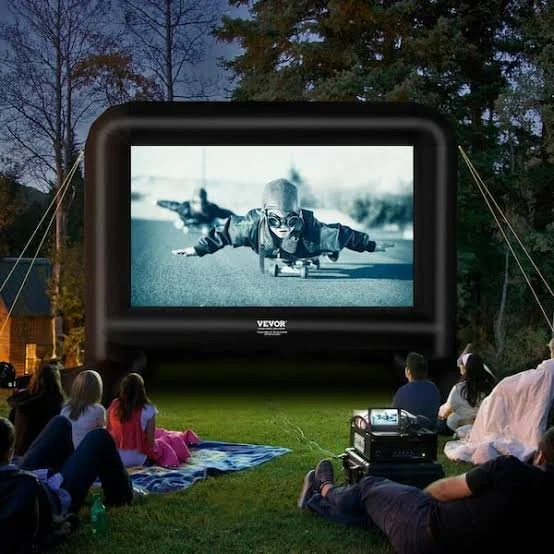 Outdoor movie party with a large inflatable projector screen set up in a backyard at night