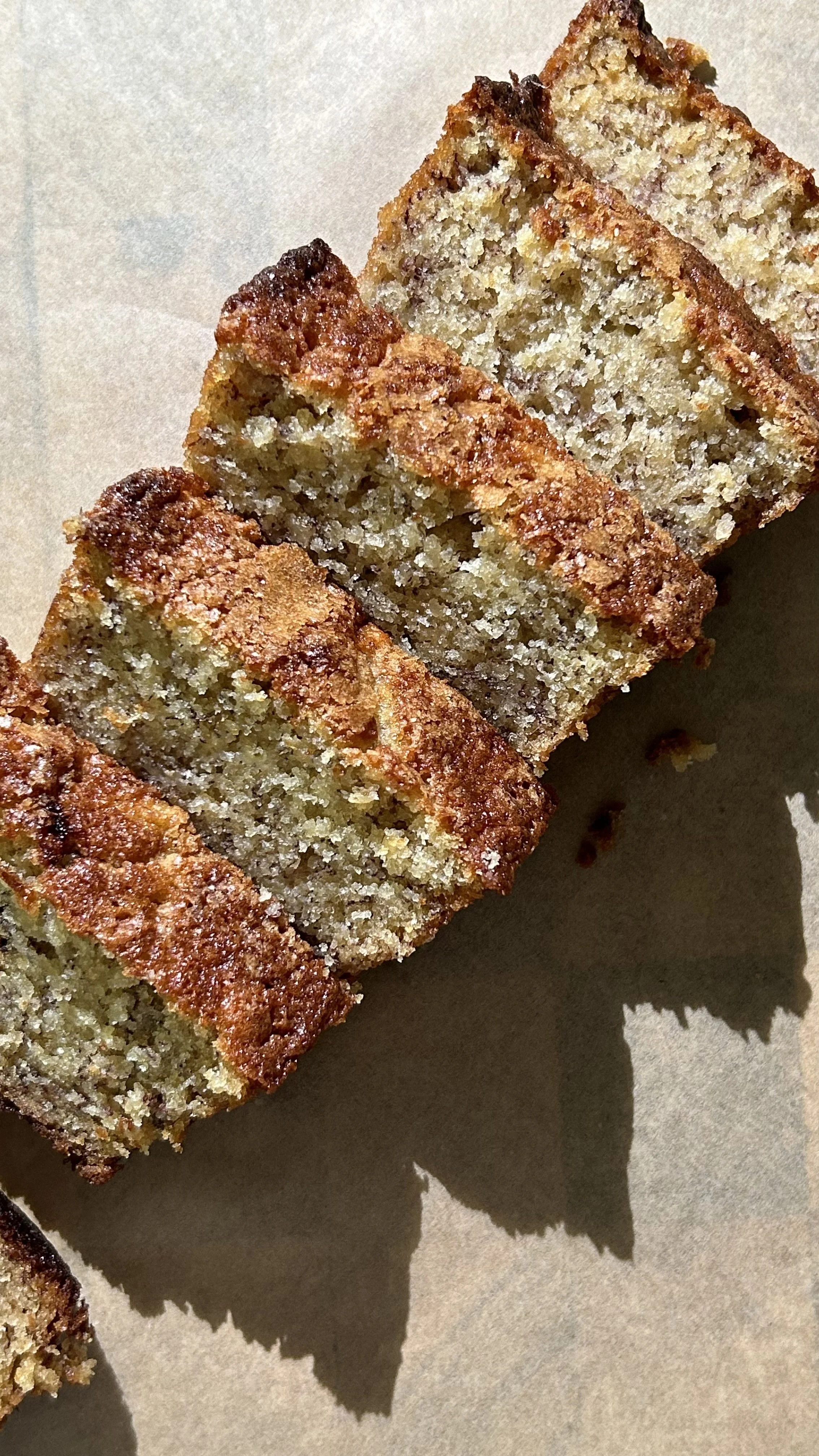 Close-up of sliced banana bread on parchment paper showing a golden-brown crust and moist interior.