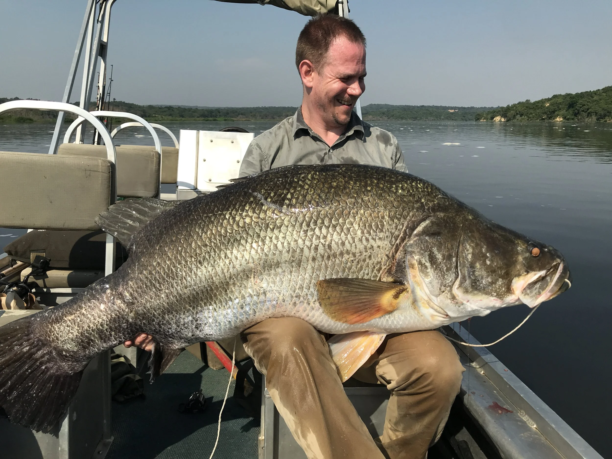 Angler holding a large Nile perch caught while fishing from a boat on Uganda's River Nile.