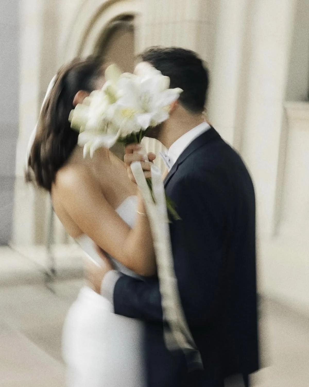 Ein Paar küsst sich auf einer Hochzeit, die Braut hält einen Blumenstrauß.
