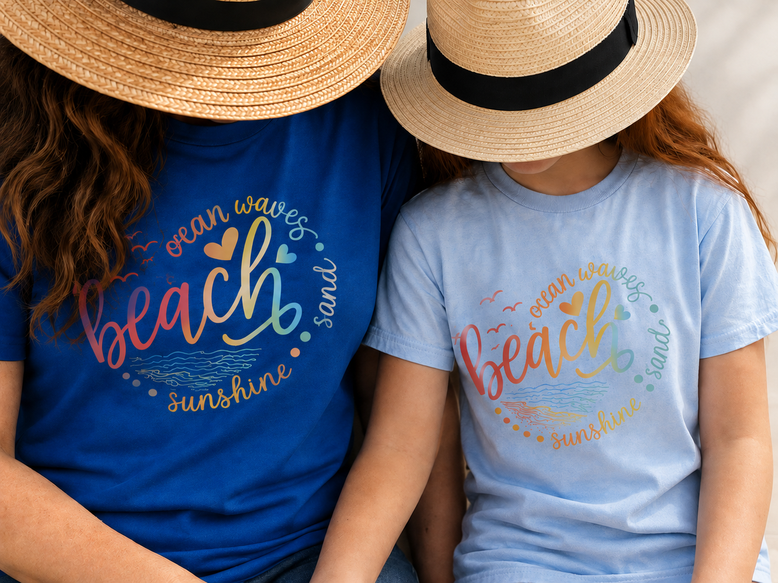 Two people wearing straw hats and colorful t-shirts with beach and sunshine-themed text, sitting close together with their arms crossed, with their heads tilted downward and facing each other.