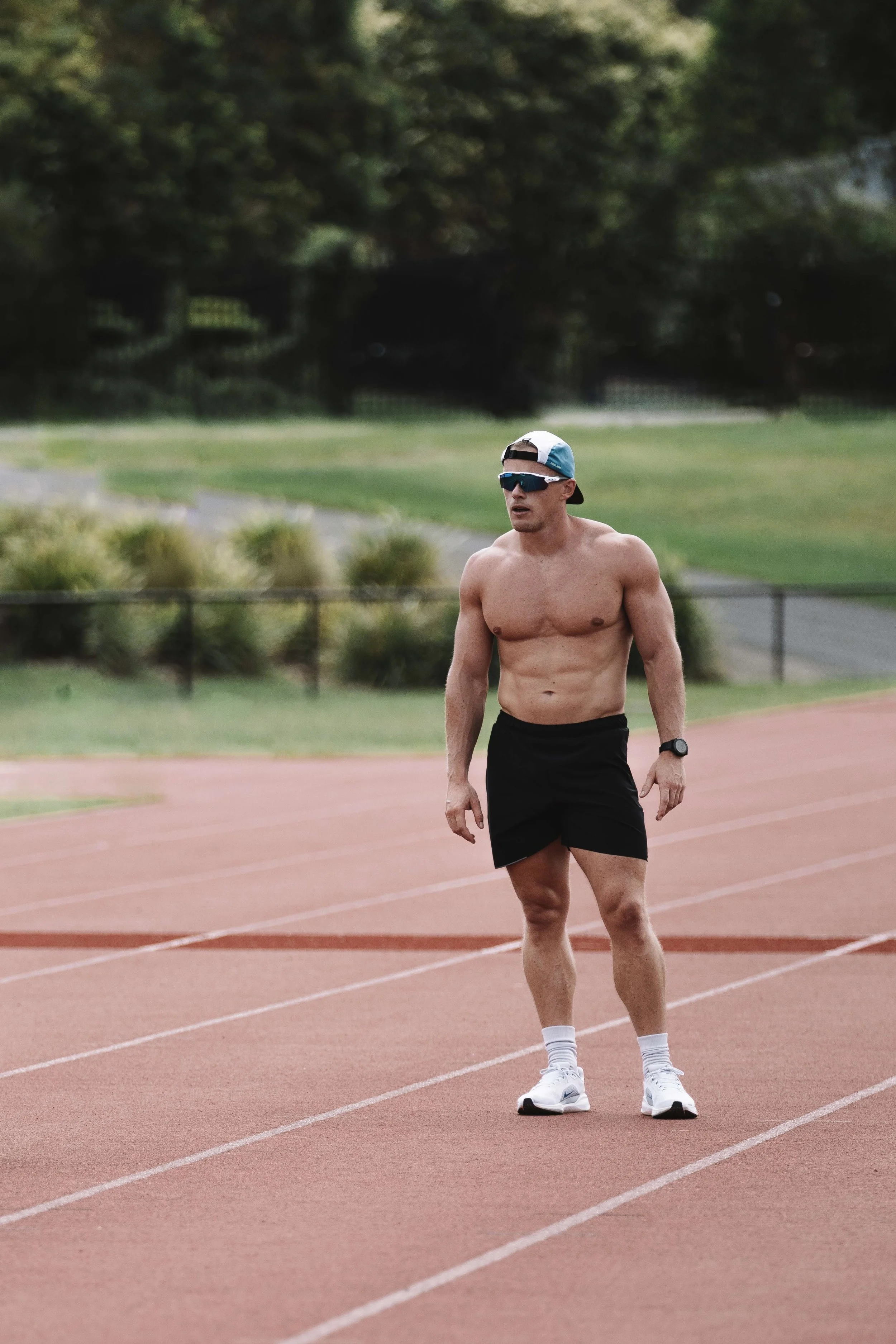 Joe Couch wearing a cap and sunglasses standing on a running track.