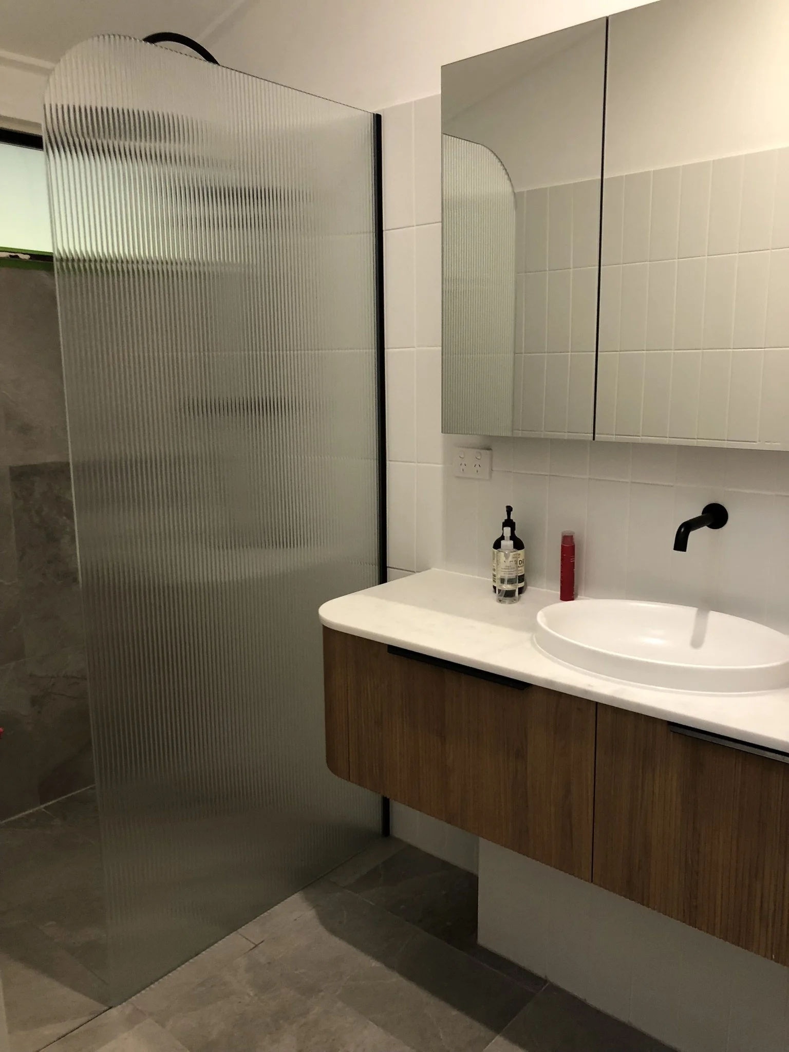 Bathroom with a mirror cabinet, a sink, soap dispenser, and toiletries on the counter.