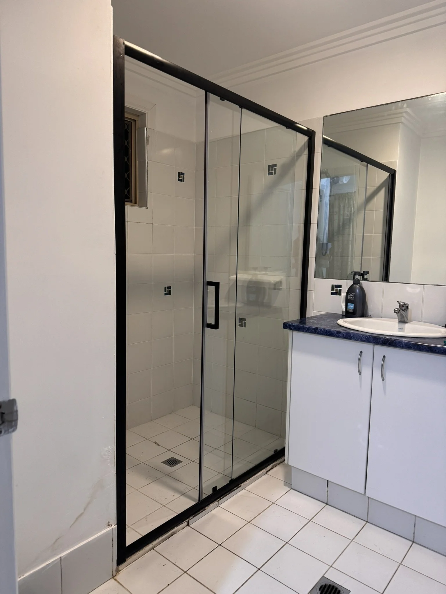 Bathroom with a shower enclosure and a sink with a mirror above it.