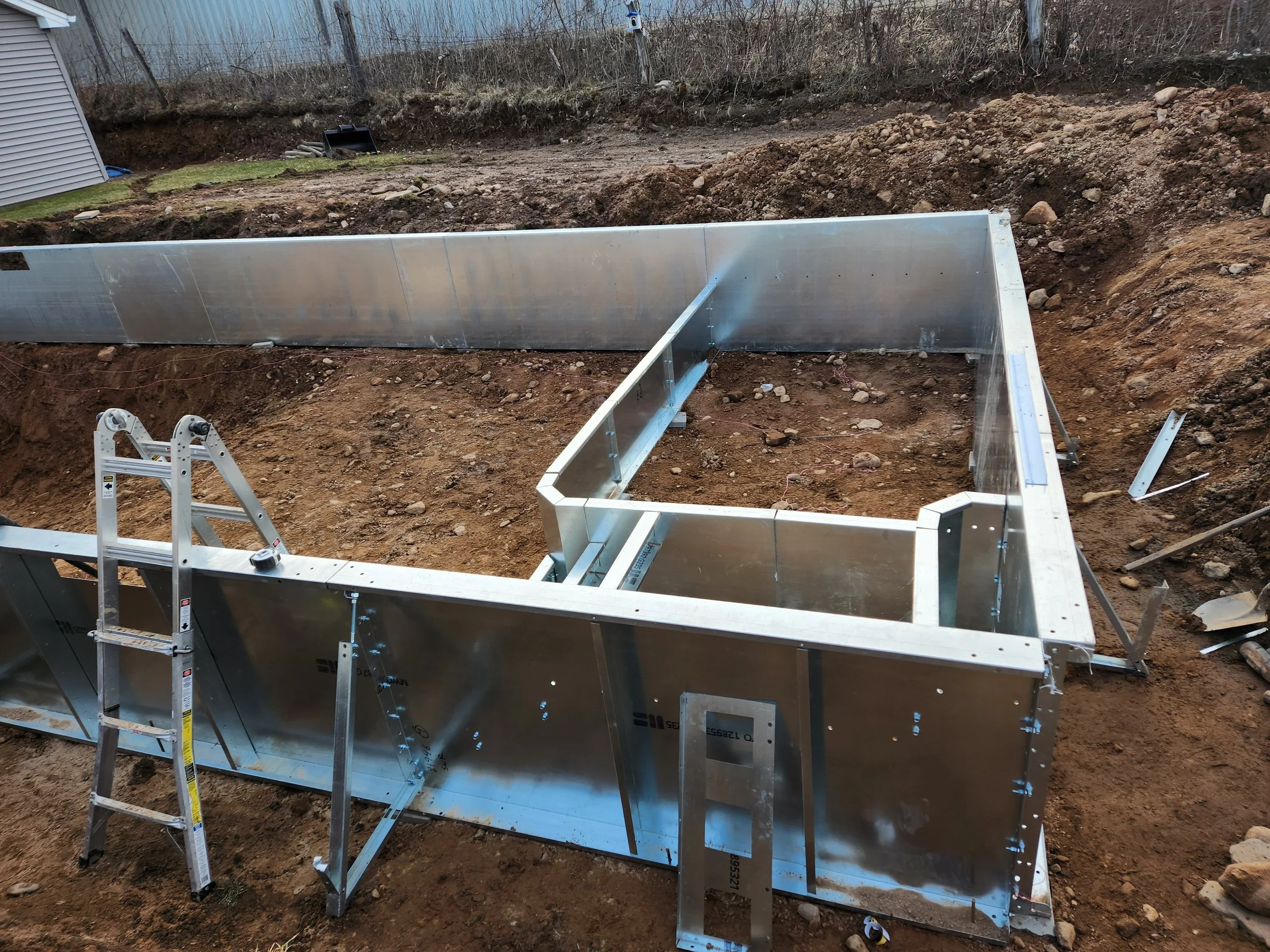 Metal framing structure at a construction site with dirt and soil around