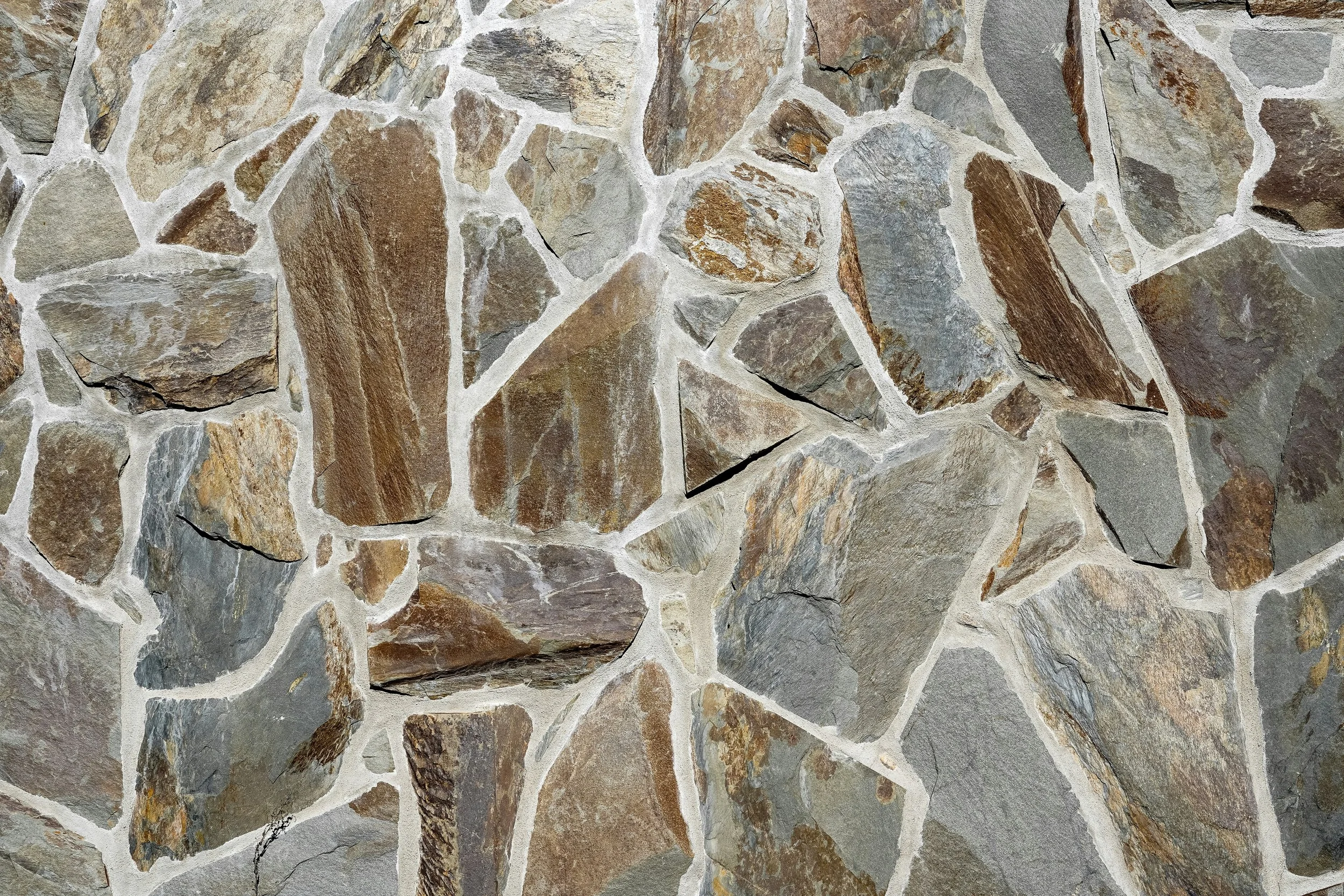 Close-up of a rustic stone wall made from irregular multicolored rocks and light mortar