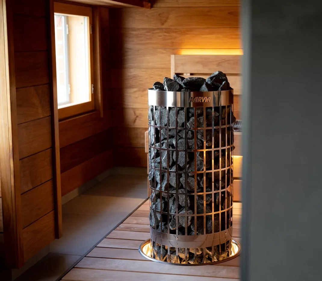 Harvia sauna heater filled with stones in a wood-paneled sauna