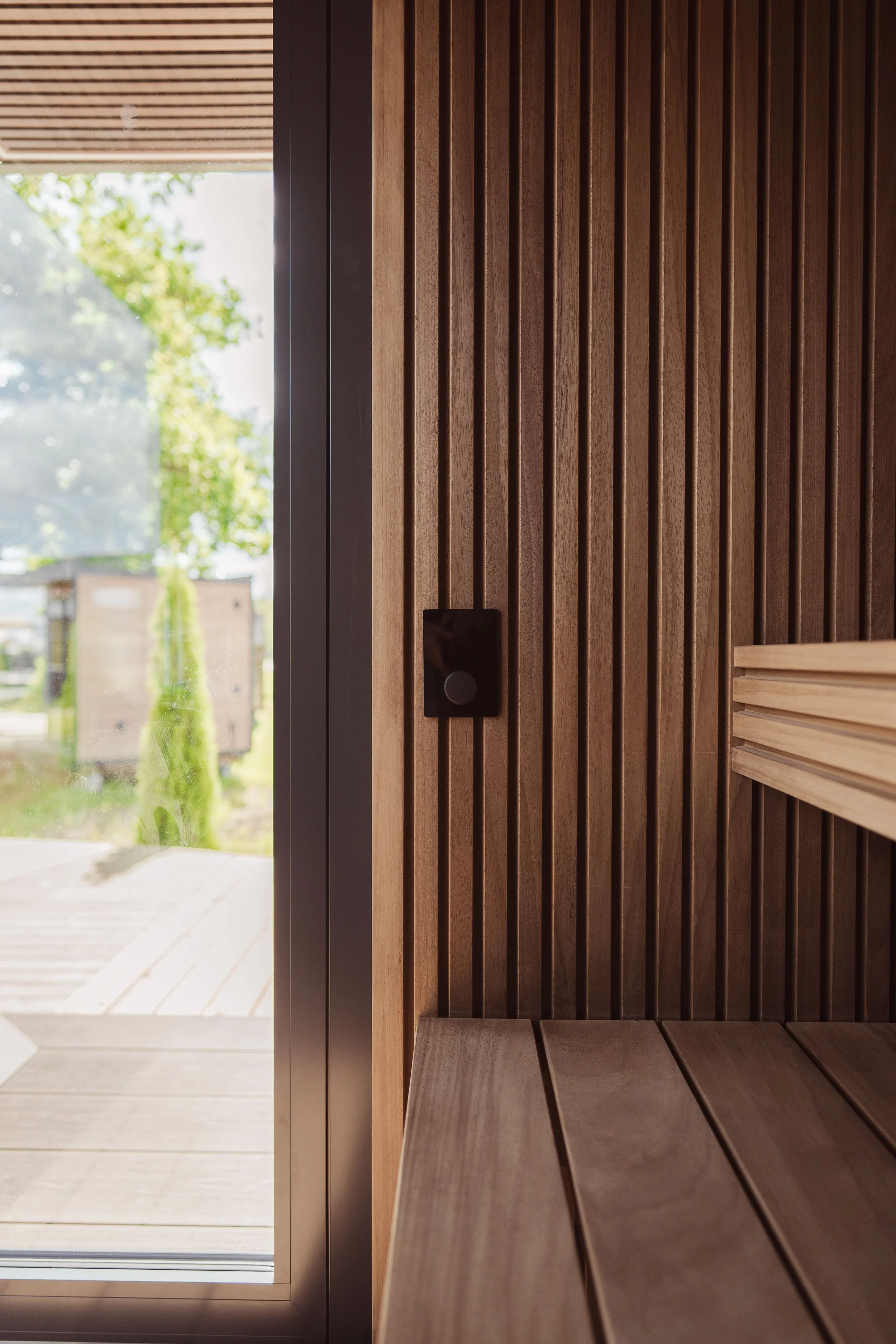 Close-up of a modern wooden front door with vertical slats, black handle, and window beside it