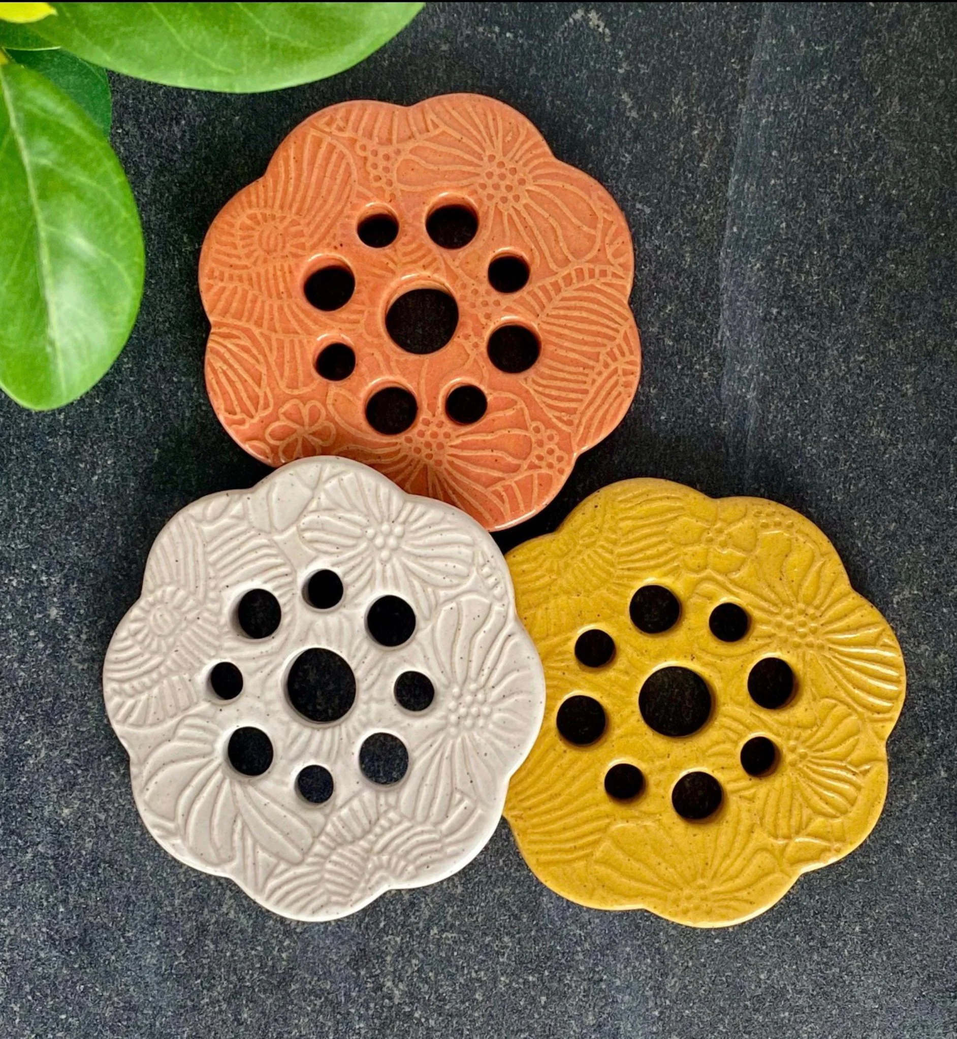 Close-up of three decorative flower-frogs in white, orange, and yellow. Place on mason jars for a cute flower display.