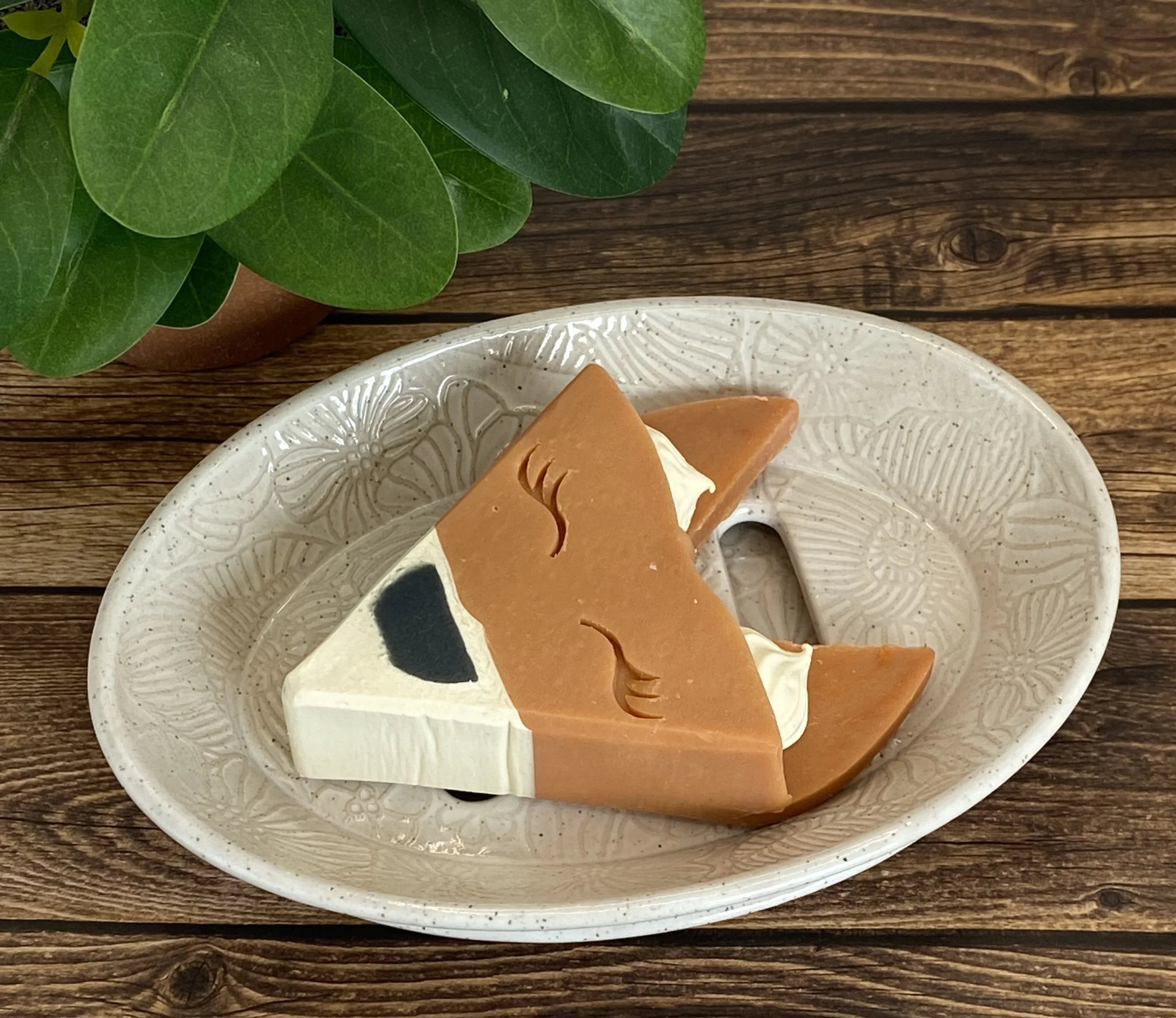 A white decorative oval ceramic soap dish with draining tray.