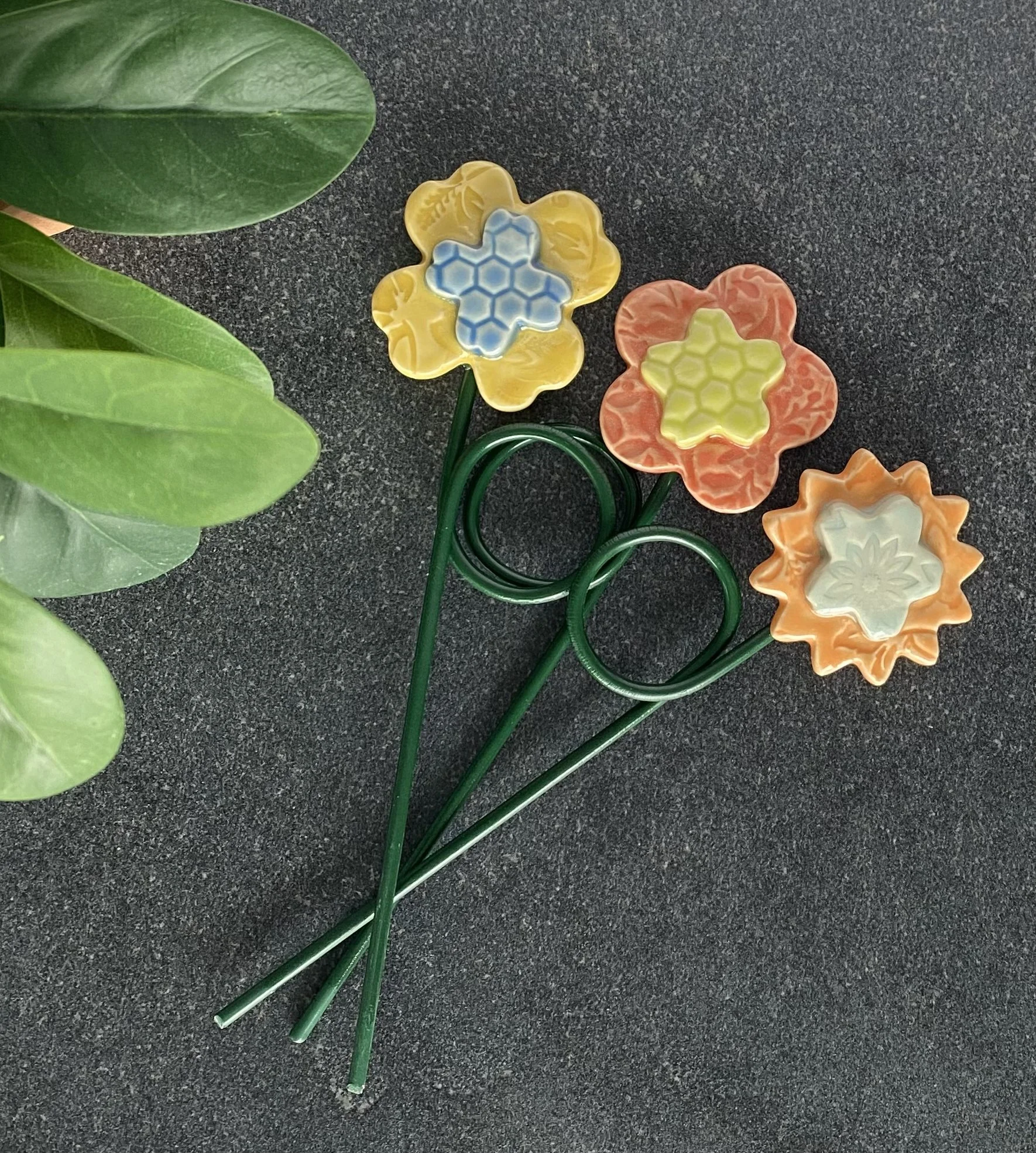 Decorative and colorful ceramic flowers with metal green stems.