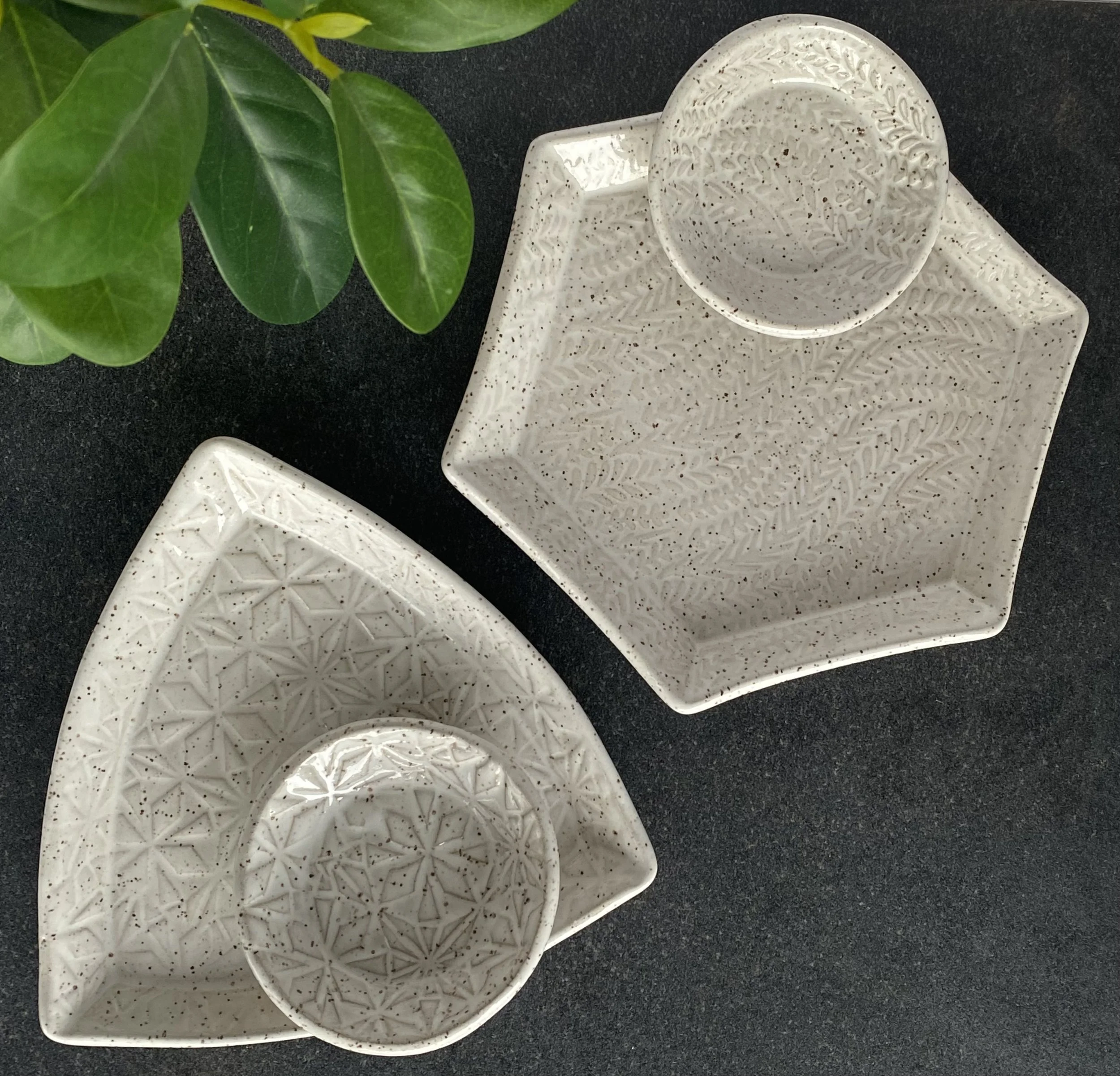 White speckled ceramic dishware and trinket trays with textured patterns. Round, triangular, and hexagon shaped jewelry trays.