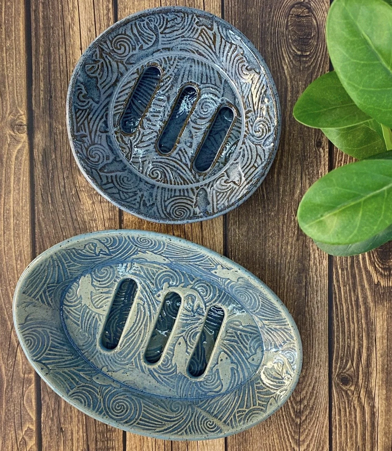 Two decorative ceramic self-draining oval and round fish / wave pattern soap dishes.