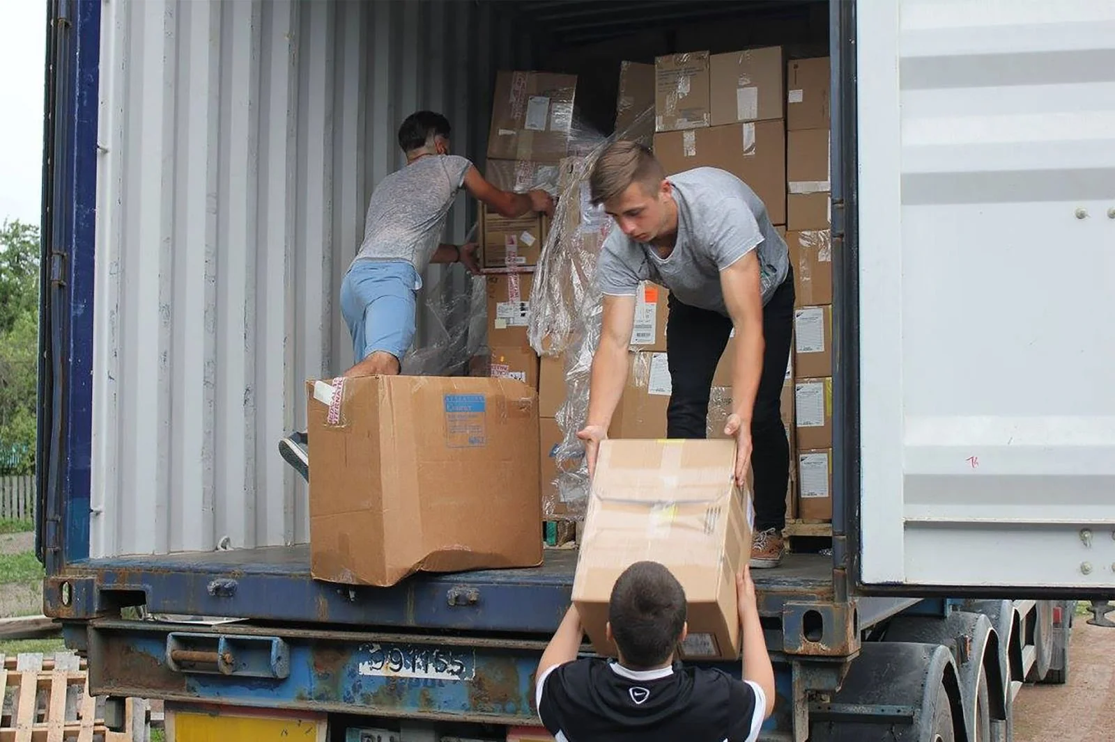 People loading and unloading boxes from a shipping container truck.