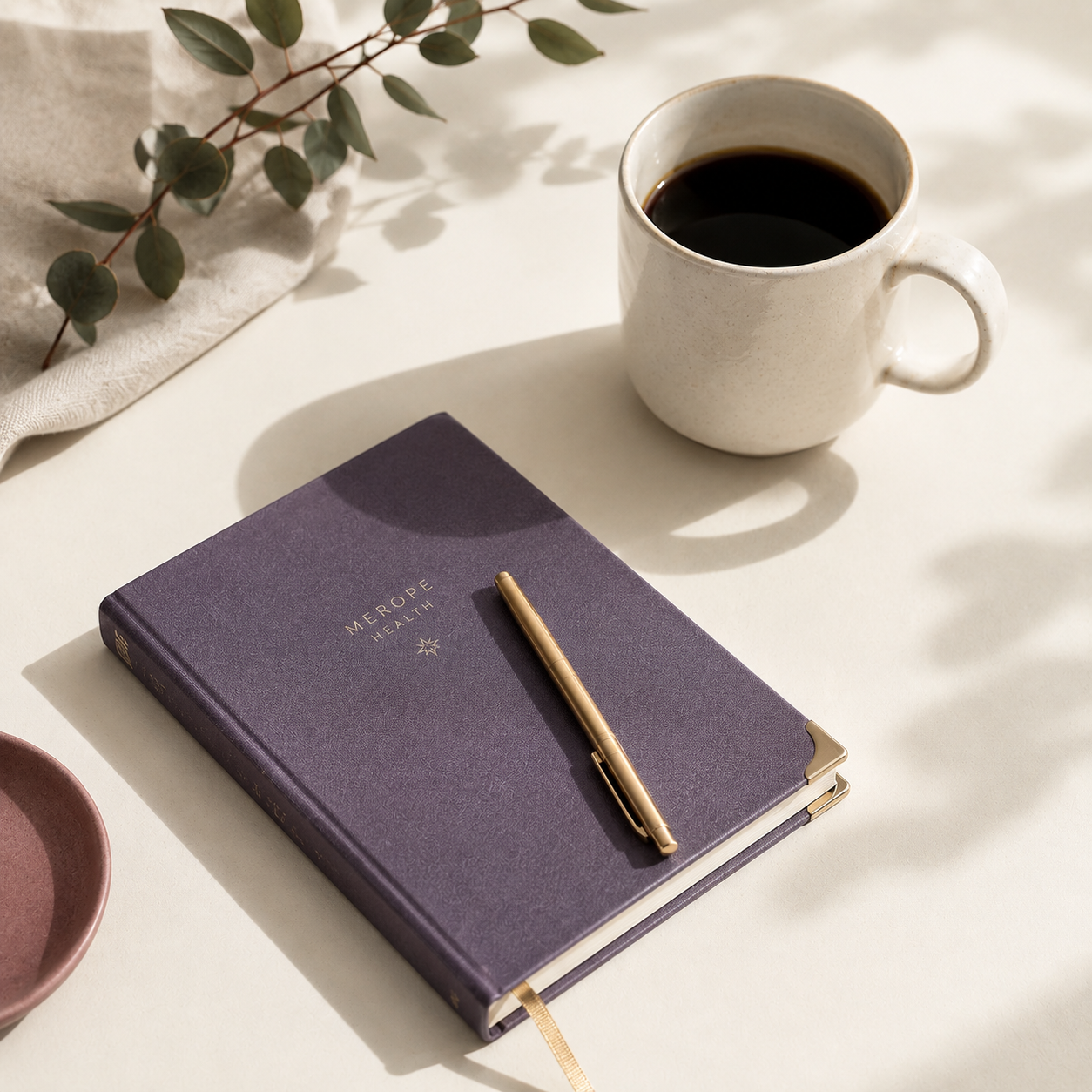 Coffee, a notebook, and a pen on a table.