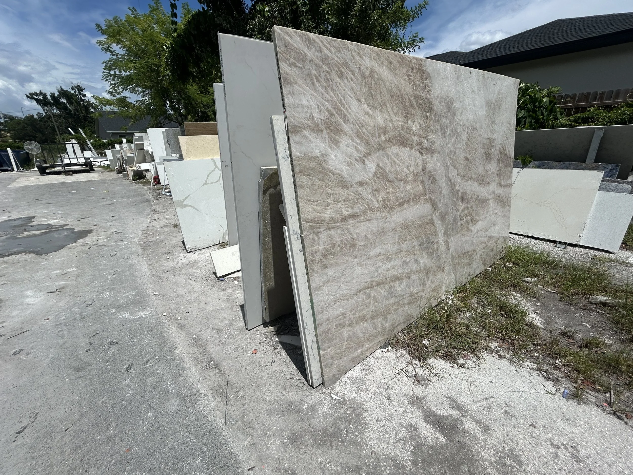 Large slabs of marble or stone standing upright outdoors, with other stone pieces and trees in the background.