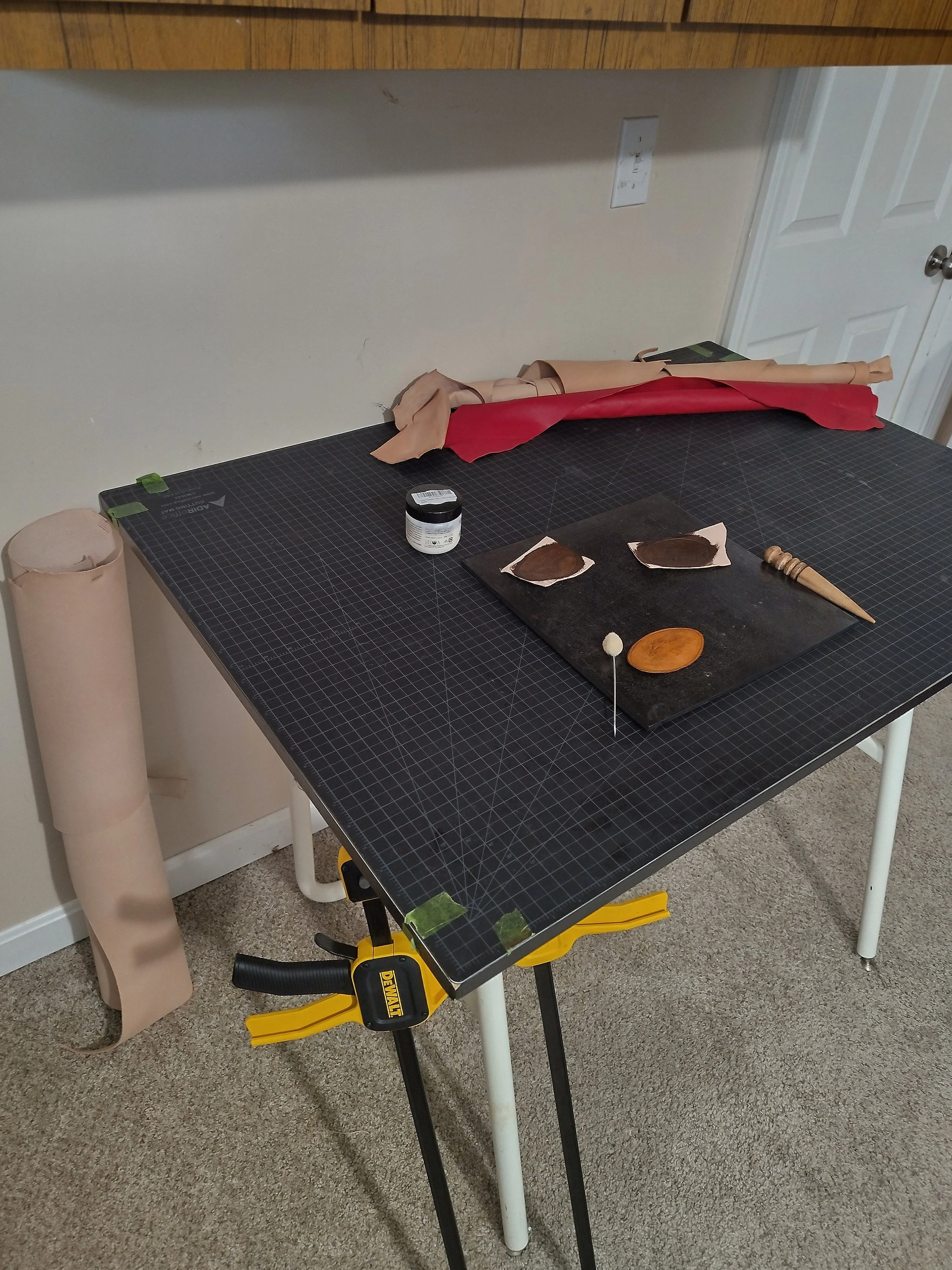 A close up picture of a drafting table covered in leatherworking supplies.