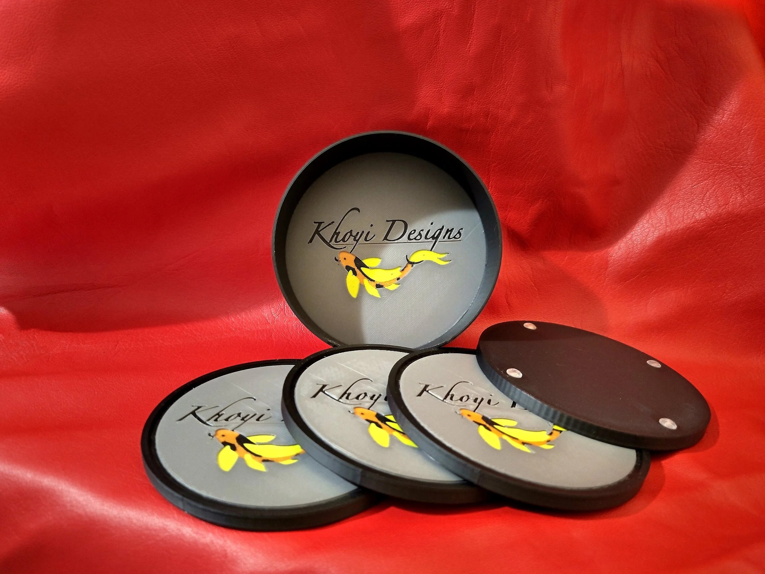 3D printed coasters with holder, displaying the Khoyi Designs logo. The backs have non slip bumps.