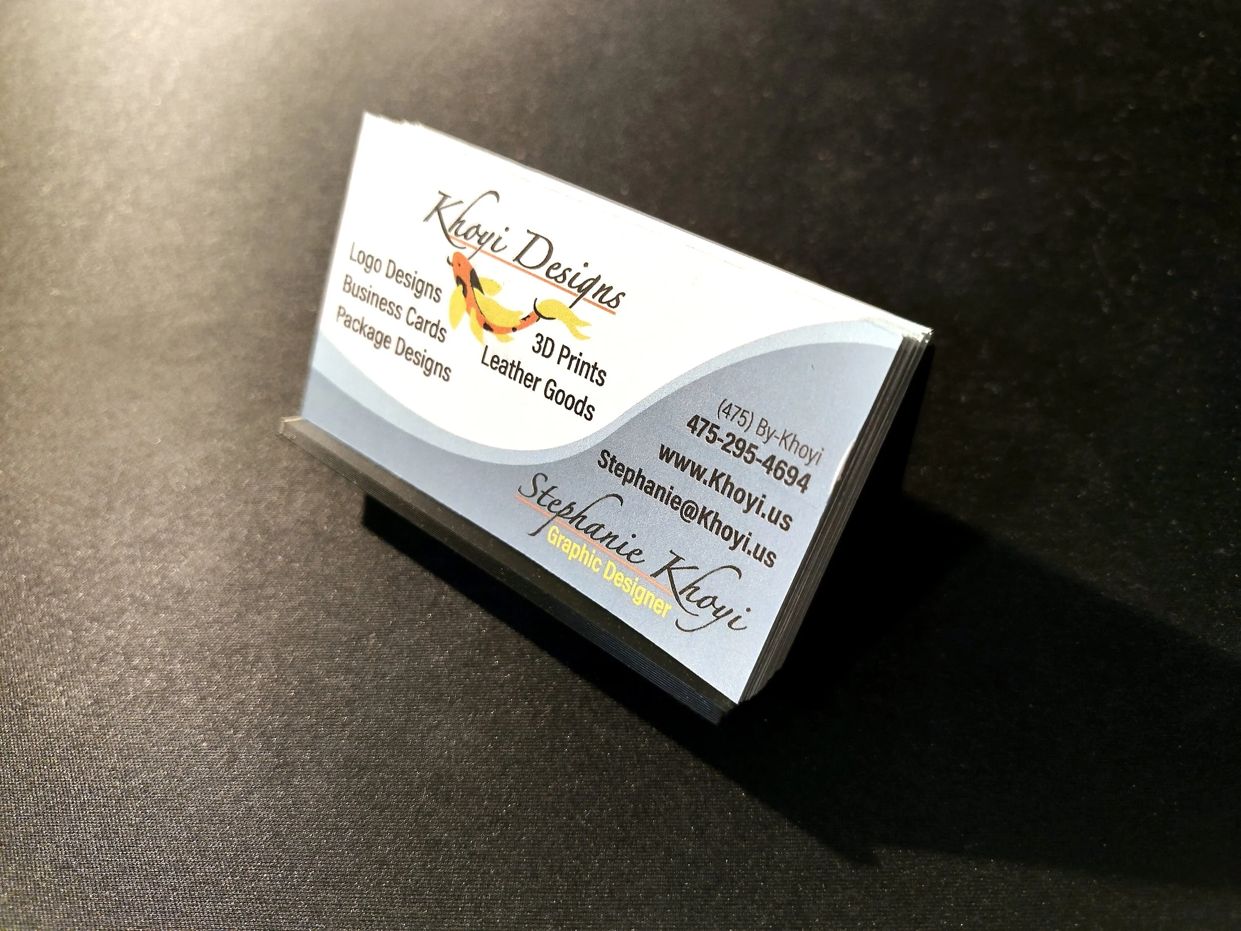 Khoyi Designs business cards on a black card holder.