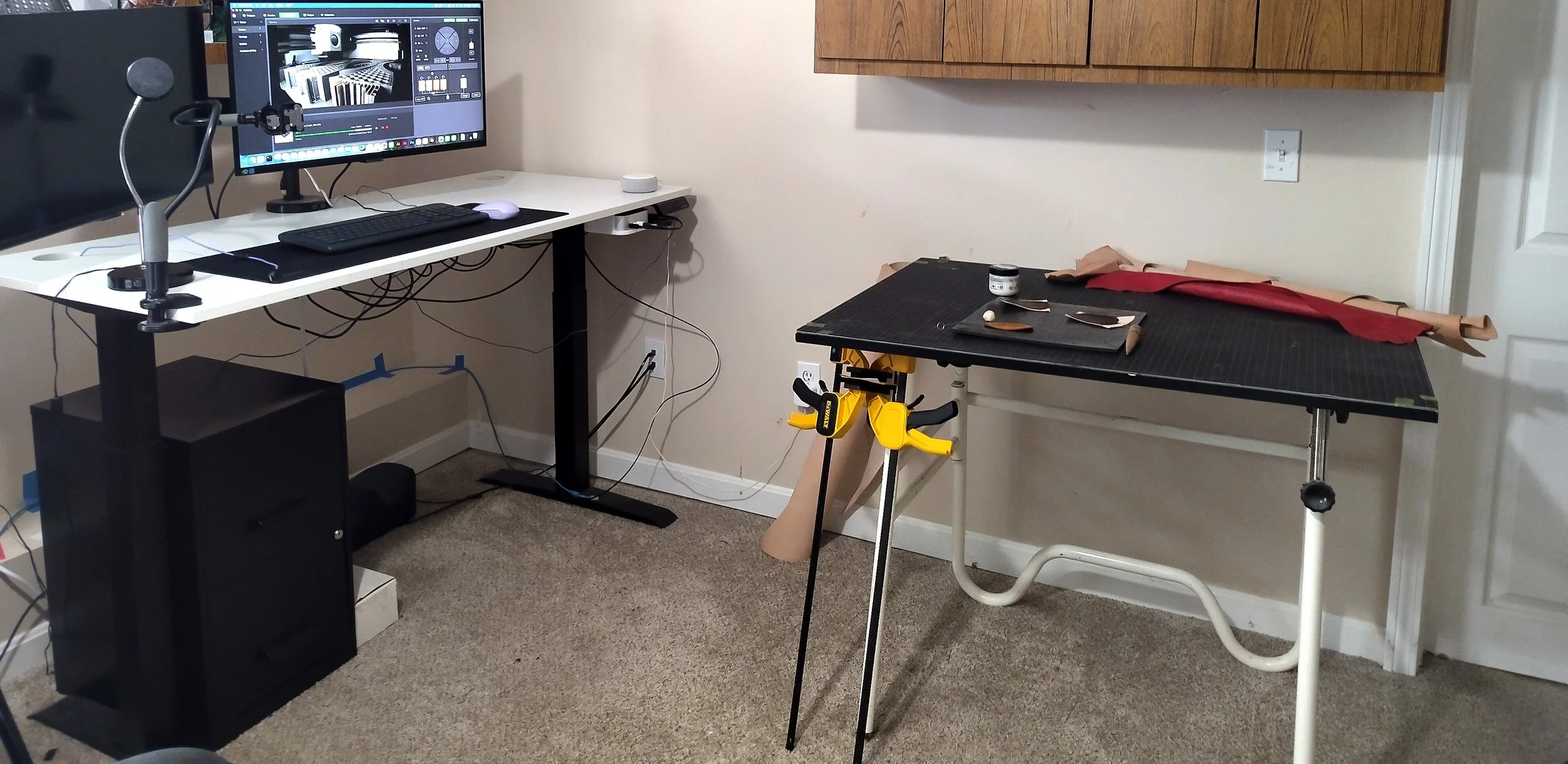 A picture of a computer standing desk perpendicular to a drafting table filled with leatherworking equiptment.