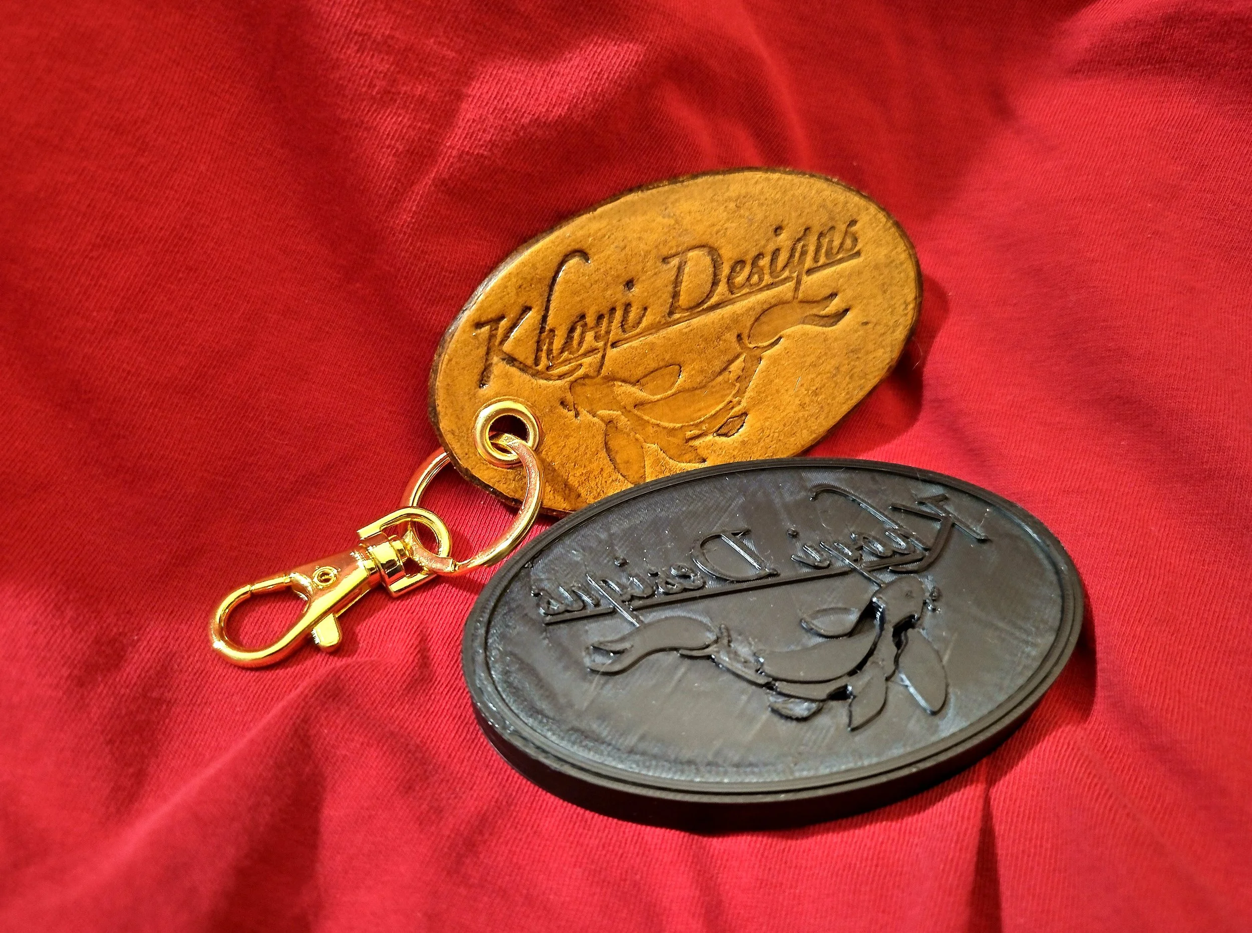A leather keychain with the Khoyi Designs logo embossed into the leather. Also pictured is the 3D printed stamp that made the impression.