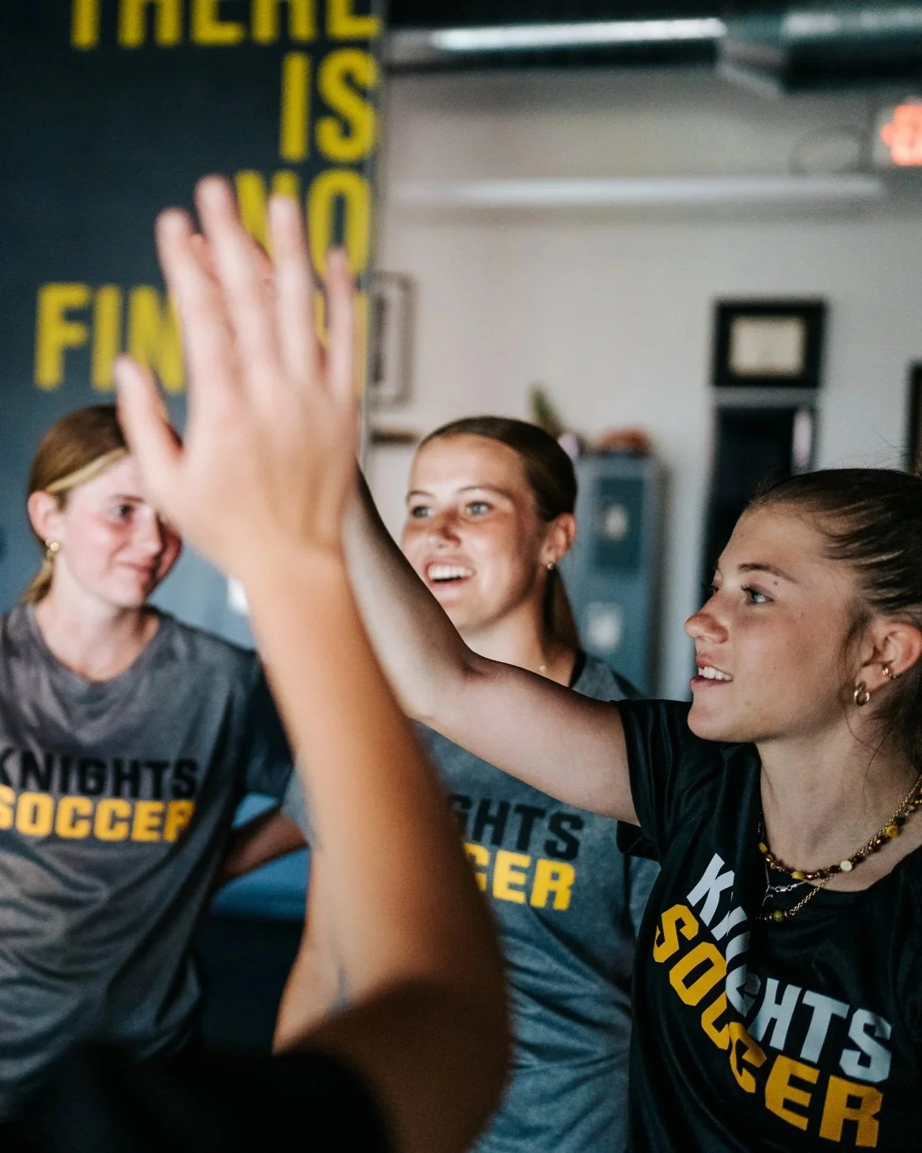 Young female soccer teammates exchange high-fives during a Breaking Lines team development training session, celebrating teamwork and connection.
