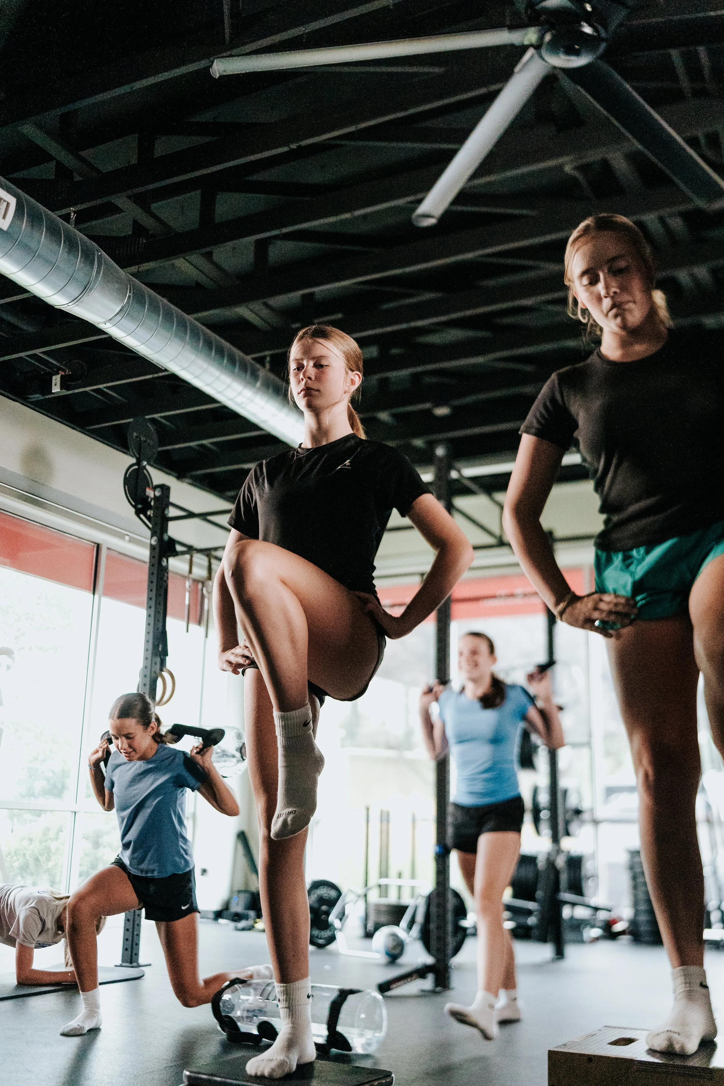 A group of young female athletes performs step-ups, lunges, and other strength and conditioning exercises during a Breaking Lines small group training session.