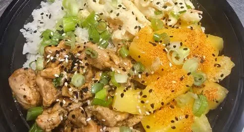 A bowl of poke with diced raw fish, sliced green onions, diced pineapple, and crushed potato chips.