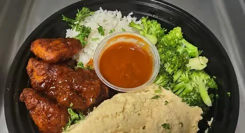 Plate with fried chicken, mashed potatoes with gravy, steamed broccoli, rice, and a side of brown gravy