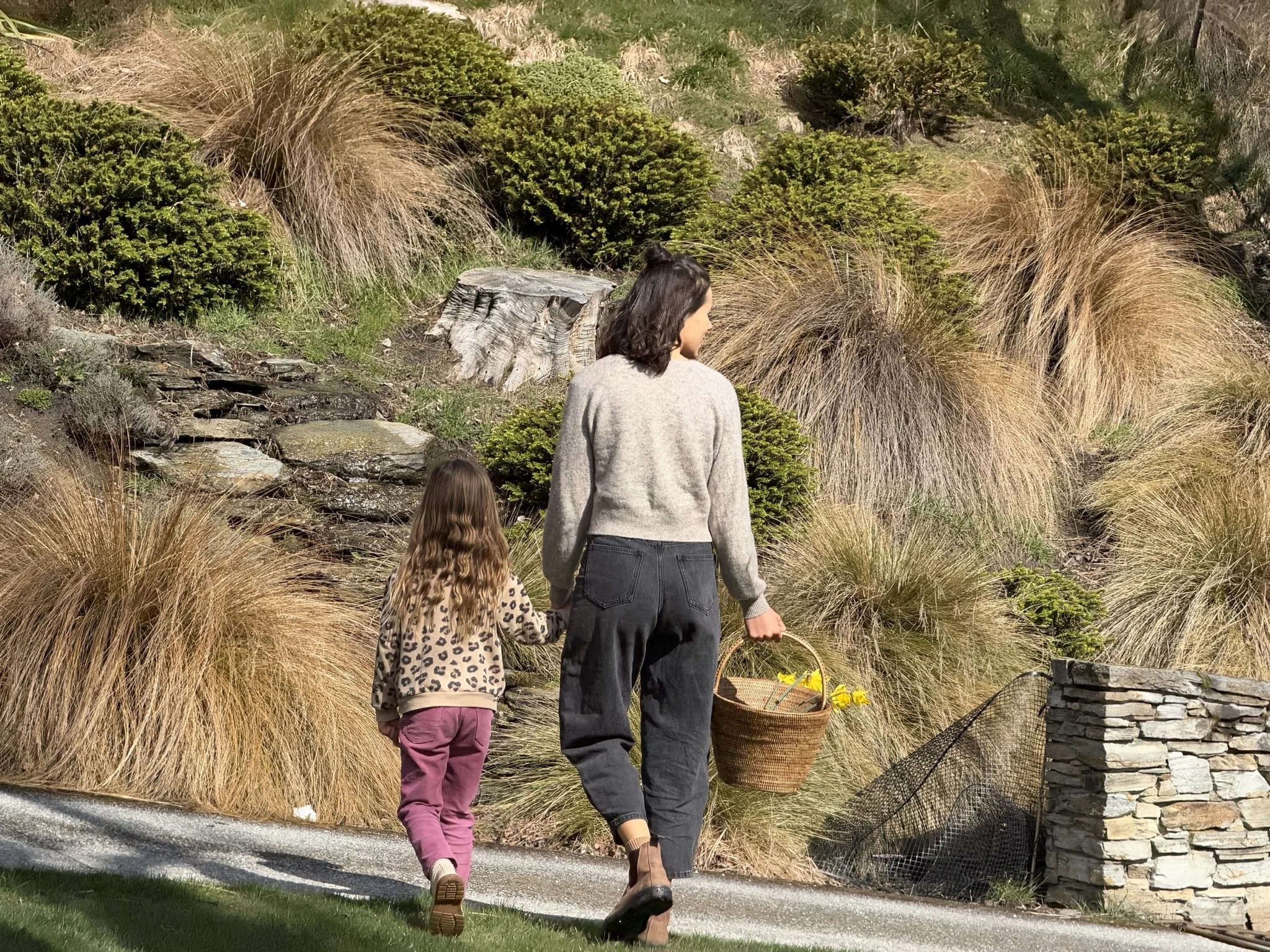Georgie a Queenstown sleep consultant walking through her garden with her daughter.